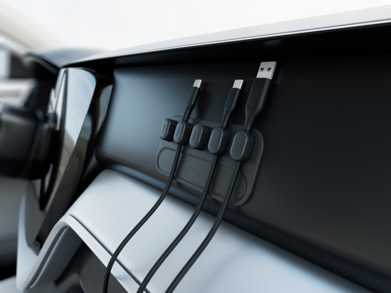 Deska rozdzielcza samochodu z czarnymi organizerami kabli trzymającymi kable USB. Kable są czarne.
