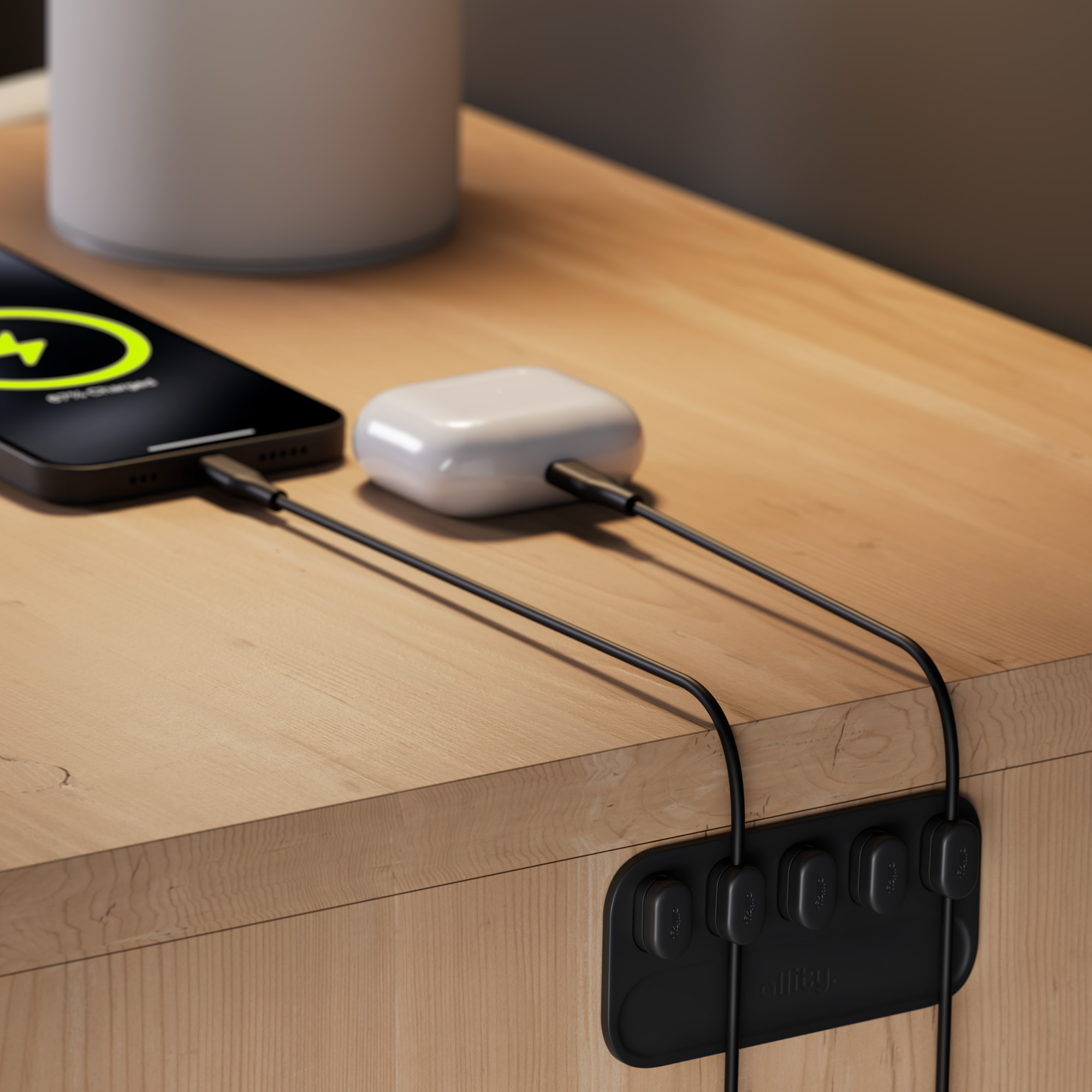 Drewniany stół z ładującym się telefonem i słuchawkami. Czarny system zarządzania kablami.