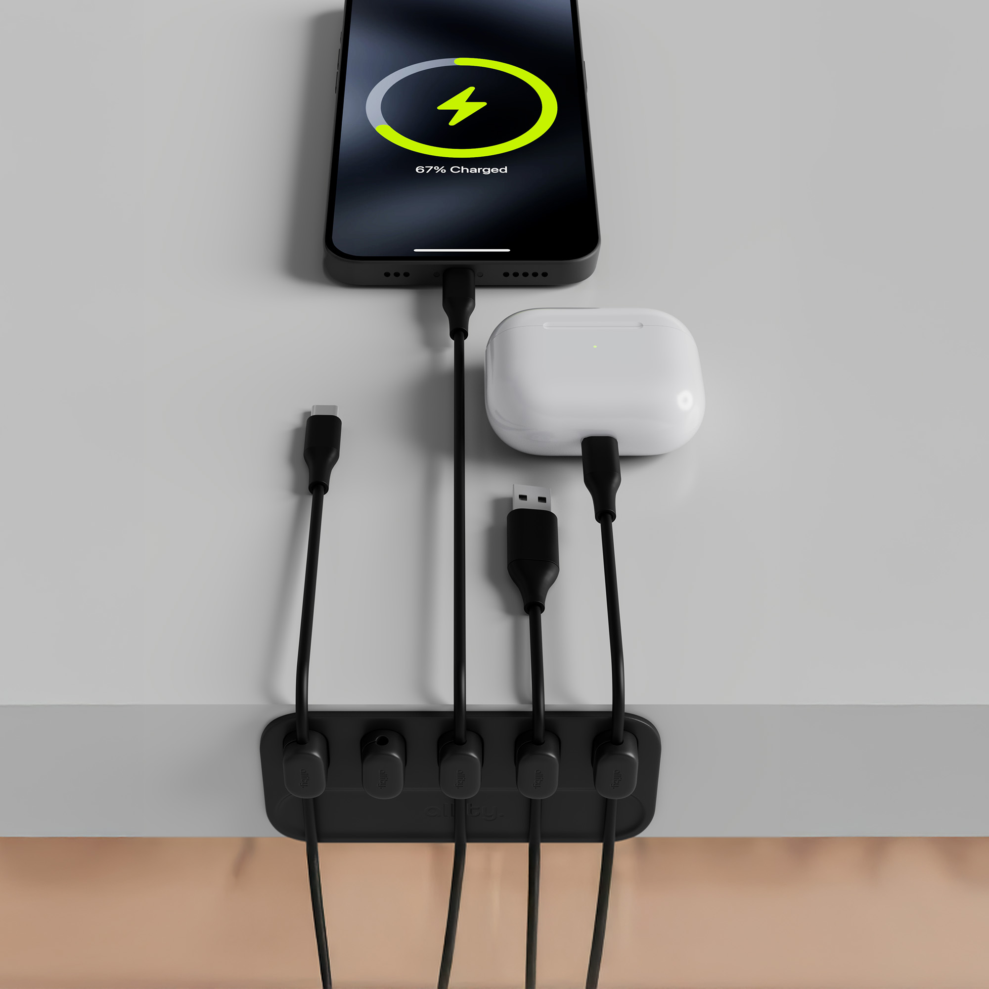 Telefon ładujący się na białym biurku. Biała bezprzewodowa stacja ładująca i AirPods obok.