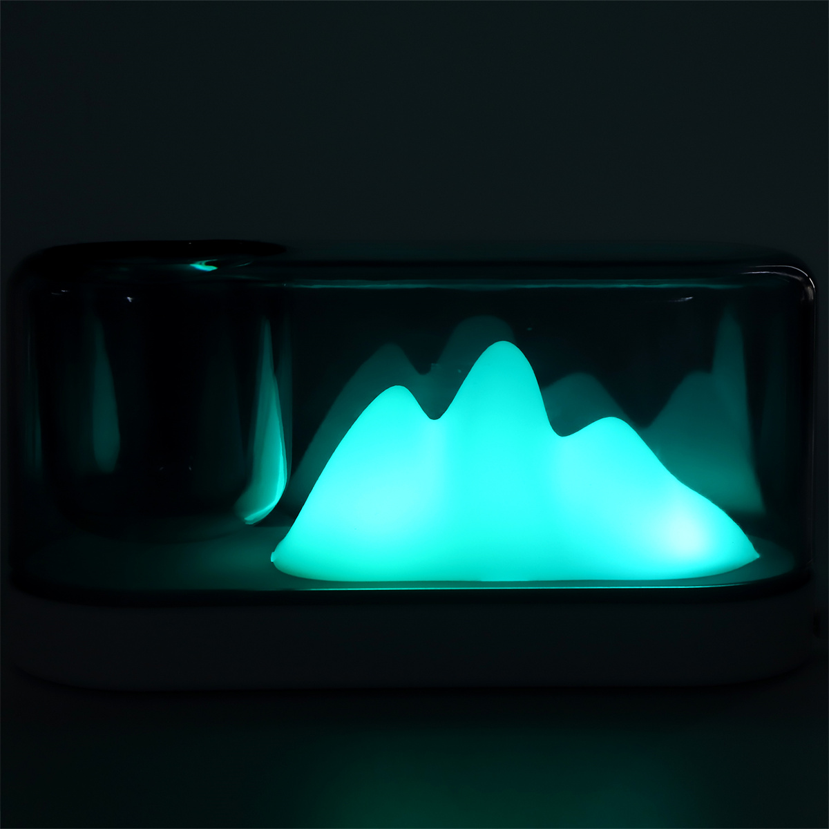 Eine leuchtende türkisfarbene bergförmige Lampe in dunkler Umgebung.