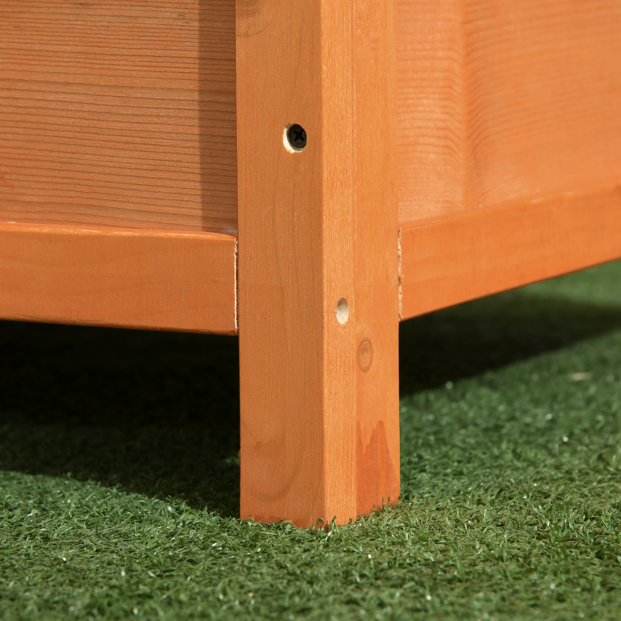Primer plano de una pata de mesa de madera. Color marrón. Fondo de hierba verde.