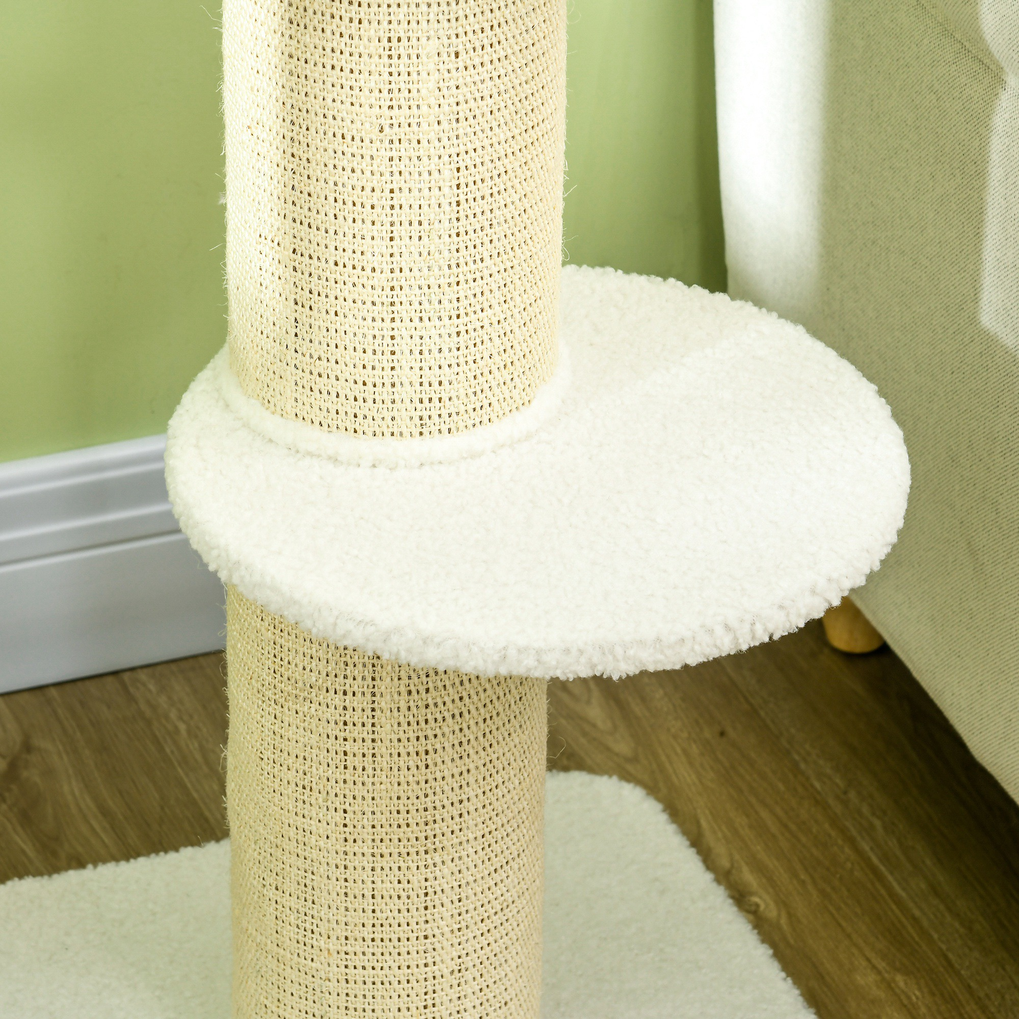 Un rascador para gatos con un pilar beige tejido y una plataforma blanca y esponjosa.