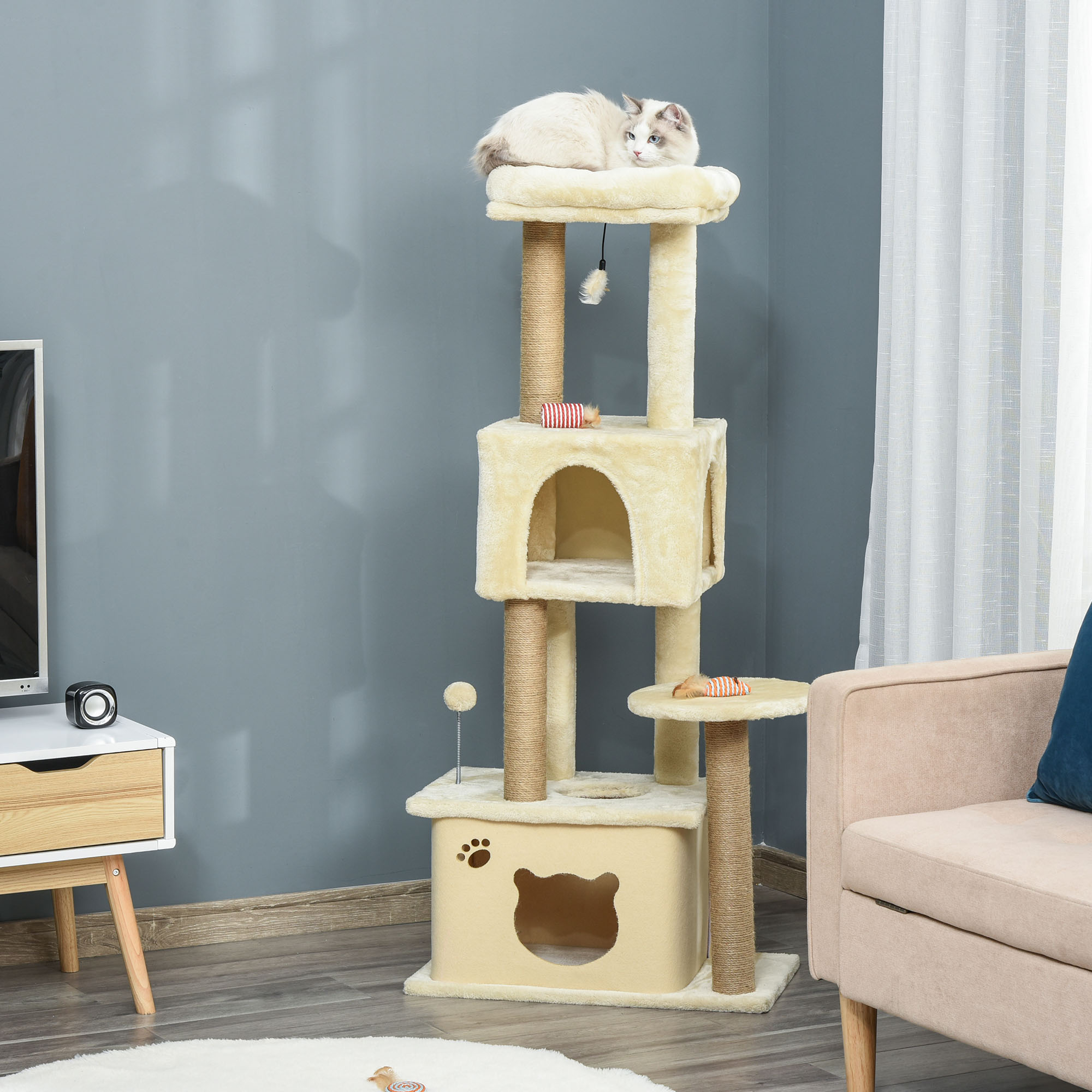 Un albero per gatti con un gatto sopra. Ha piattaforme, una cuccia e giocattoli. I colori beige e crema sono dominanti.