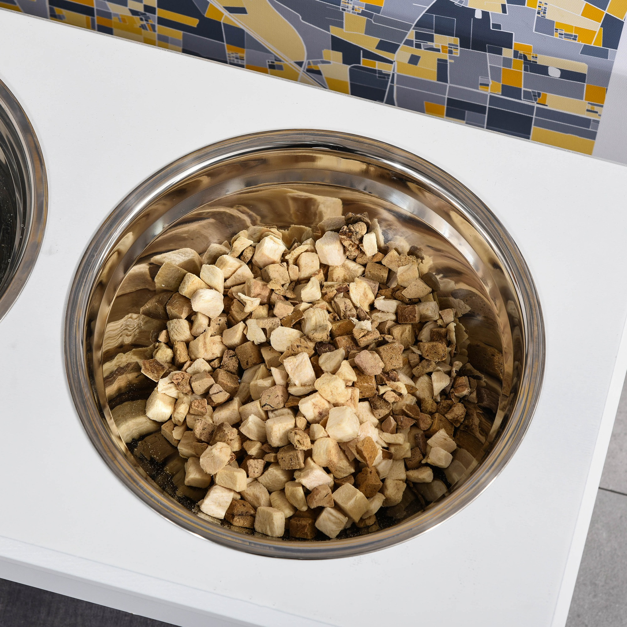 Primer plano de un cuenco de acero inoxidable para perros lleno de comida seca para perros. Está cortada en dados.