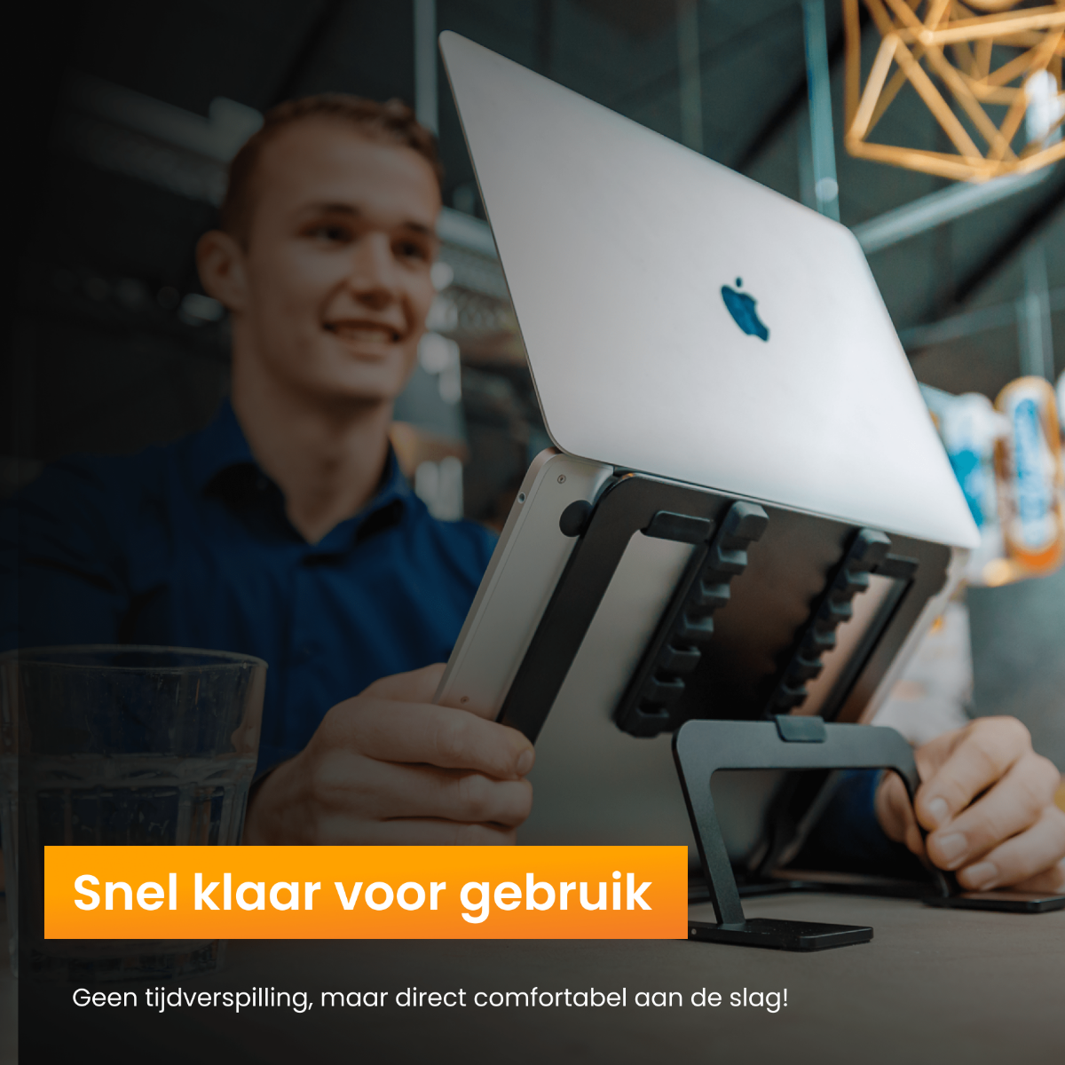 Een man die een laptop gebruikt op een zwarte laptopstandaard. De tekst zegt 'Klaar voor gebruik' in oranje.