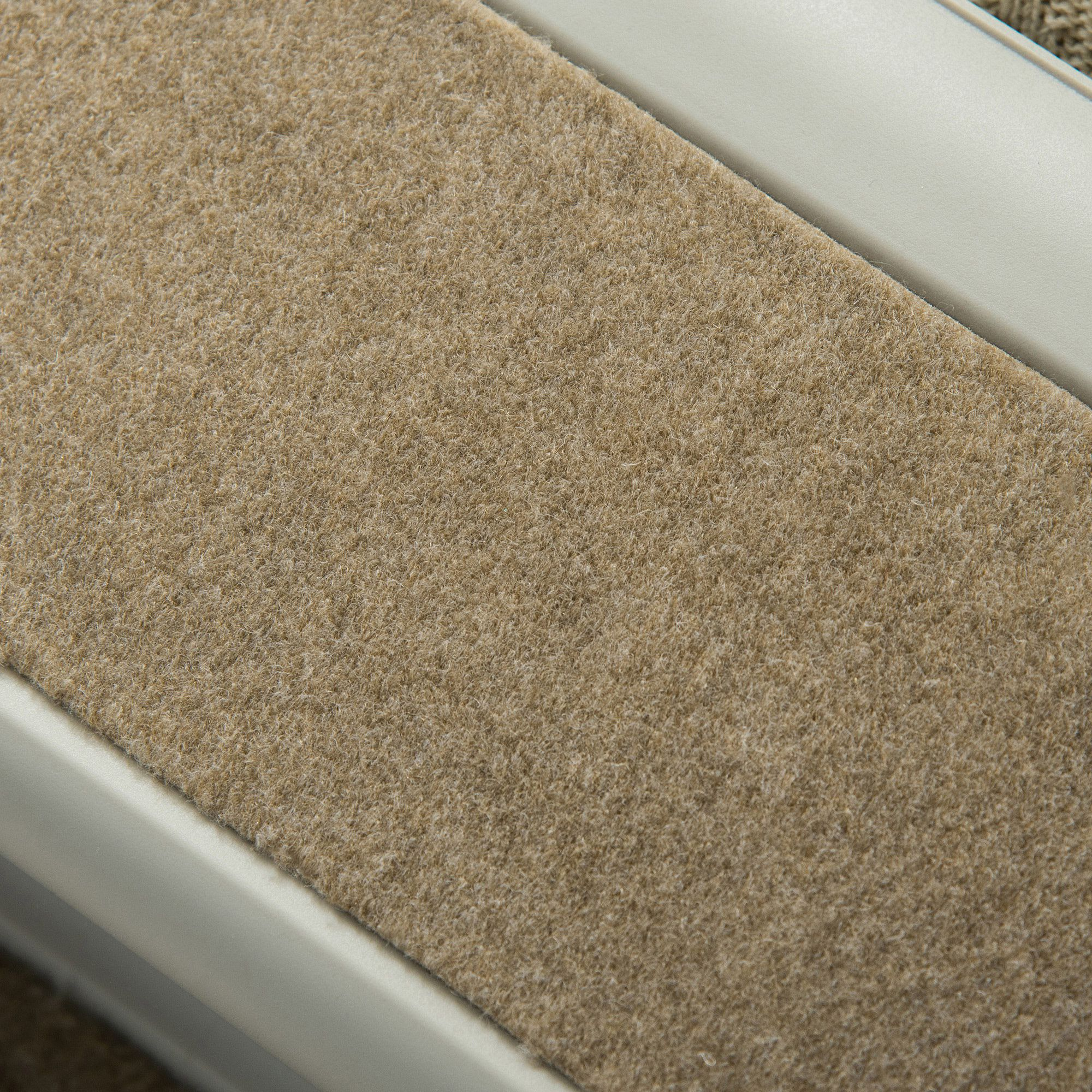 Primer plano de una rampa alfombrada con tela beige y borde blanco.