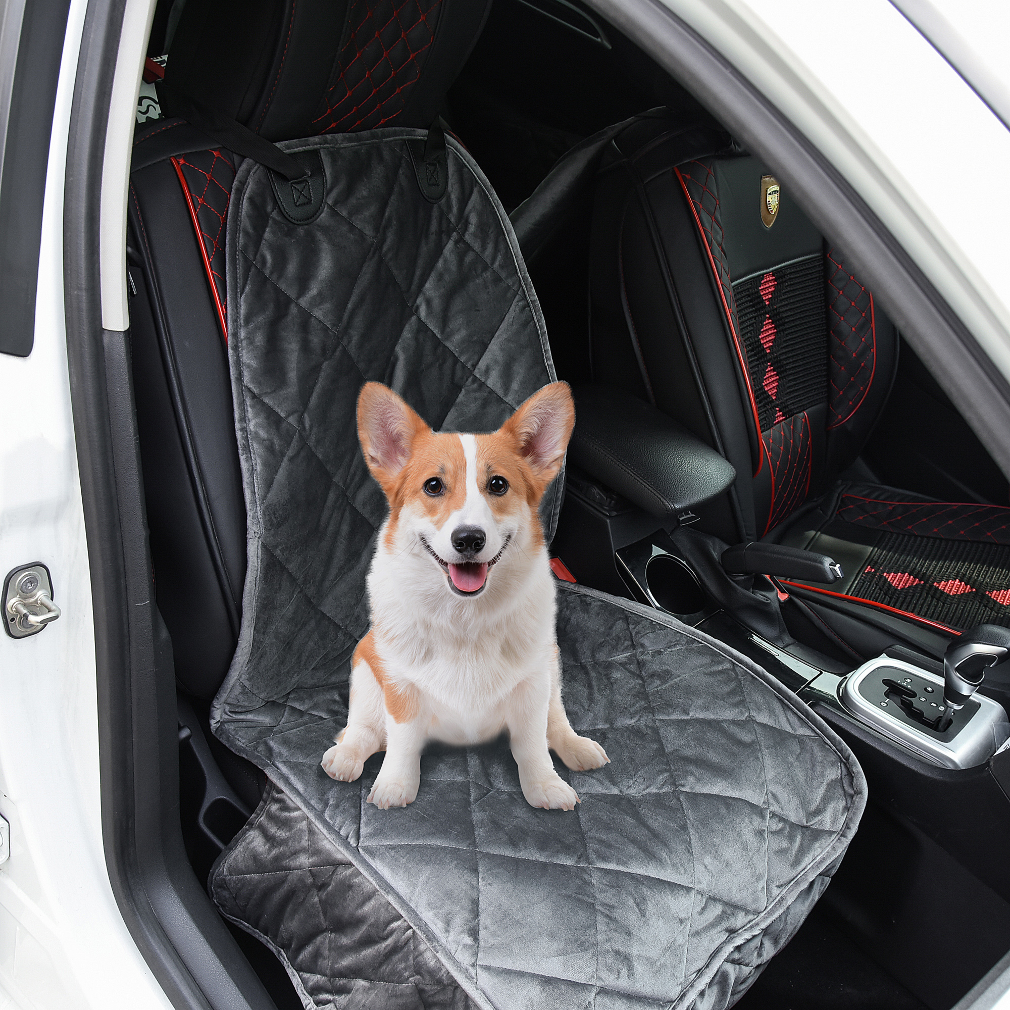 Un perro corgi se sienta en una funda de asiento de coche gris dentro de un coche. El asiento está acolchado.