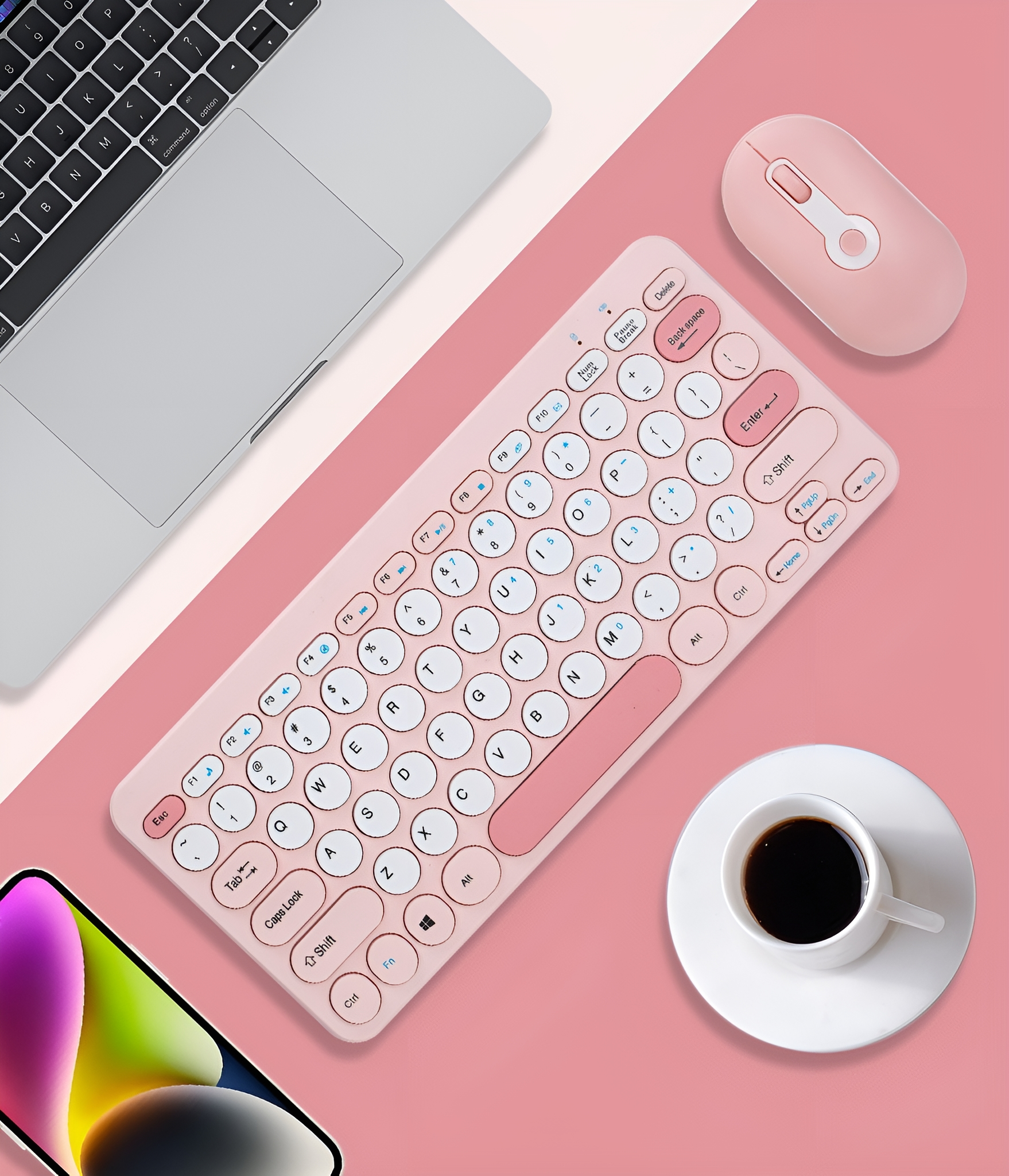 Drahtlose pinke Tastatur, Maus, Laptop und Kaffeetasse auf pinkem Hintergrund. Die Tastatur hat weiße Tasten.