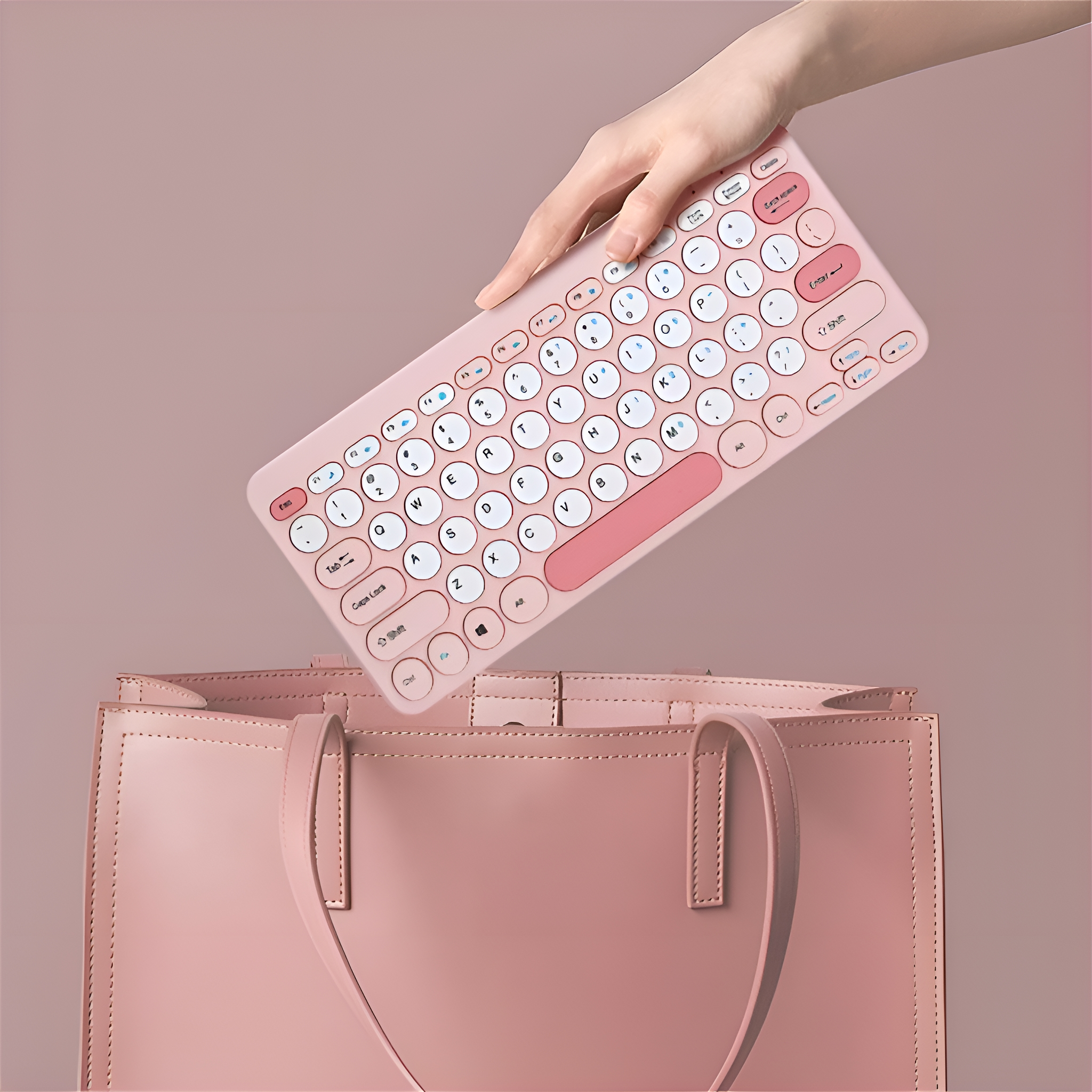 Eine Hand, die eine rosa Tastatur hält, und eine rosa Tasche im Hintergrund.