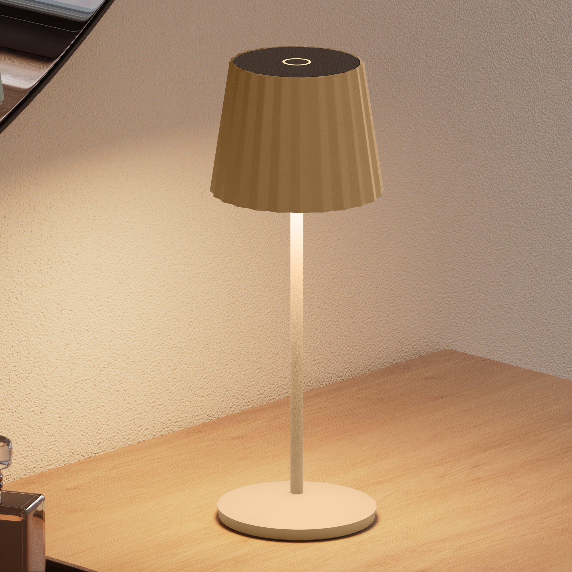 Eine Tischlampe. Beigefarbener Schirm und Fuß, weißer Stiel. Auf Holztisch, neutraler Wandhintergrund.