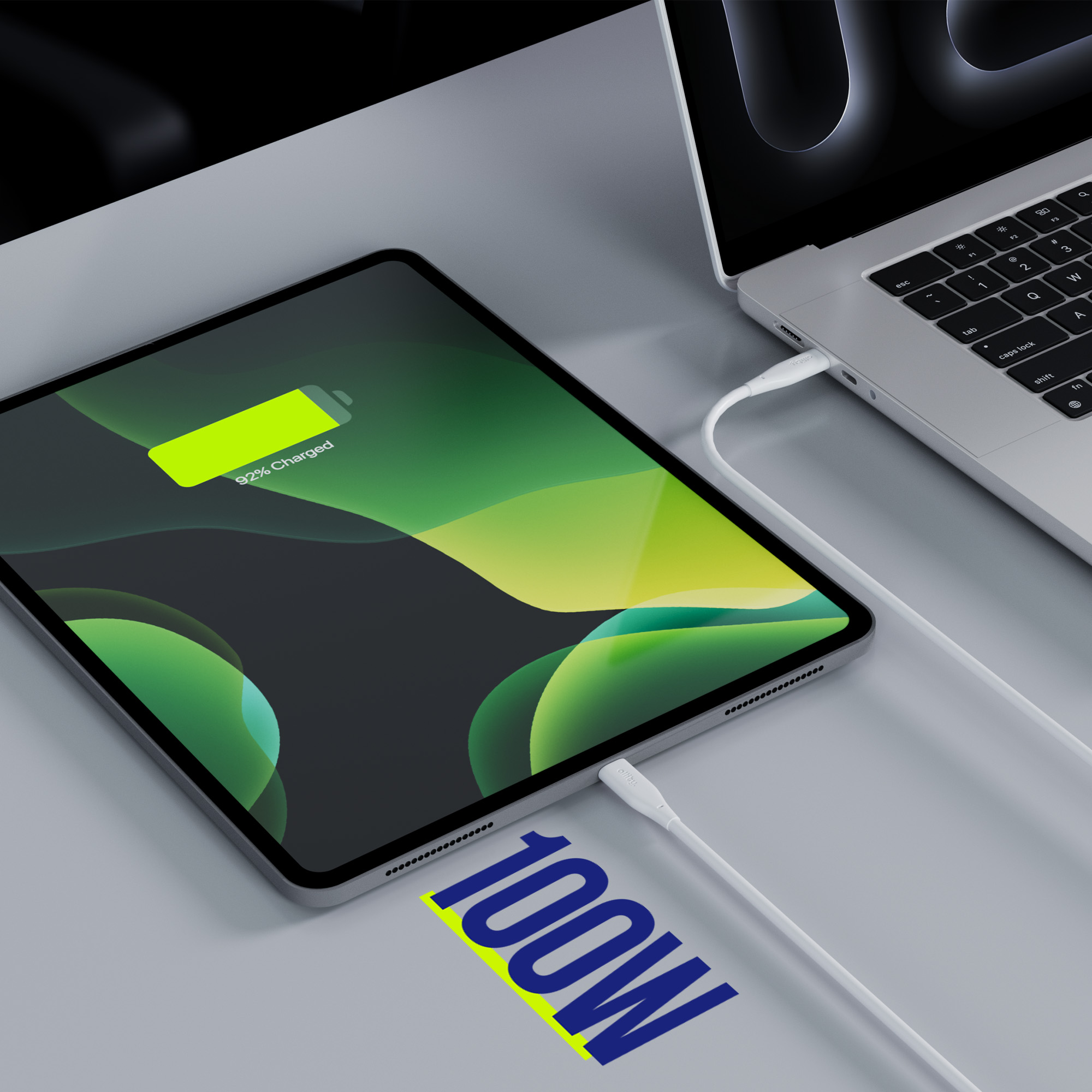 Tablet ładujący się białym kablem z laptopa. Słowo 100W jest podświetlone.