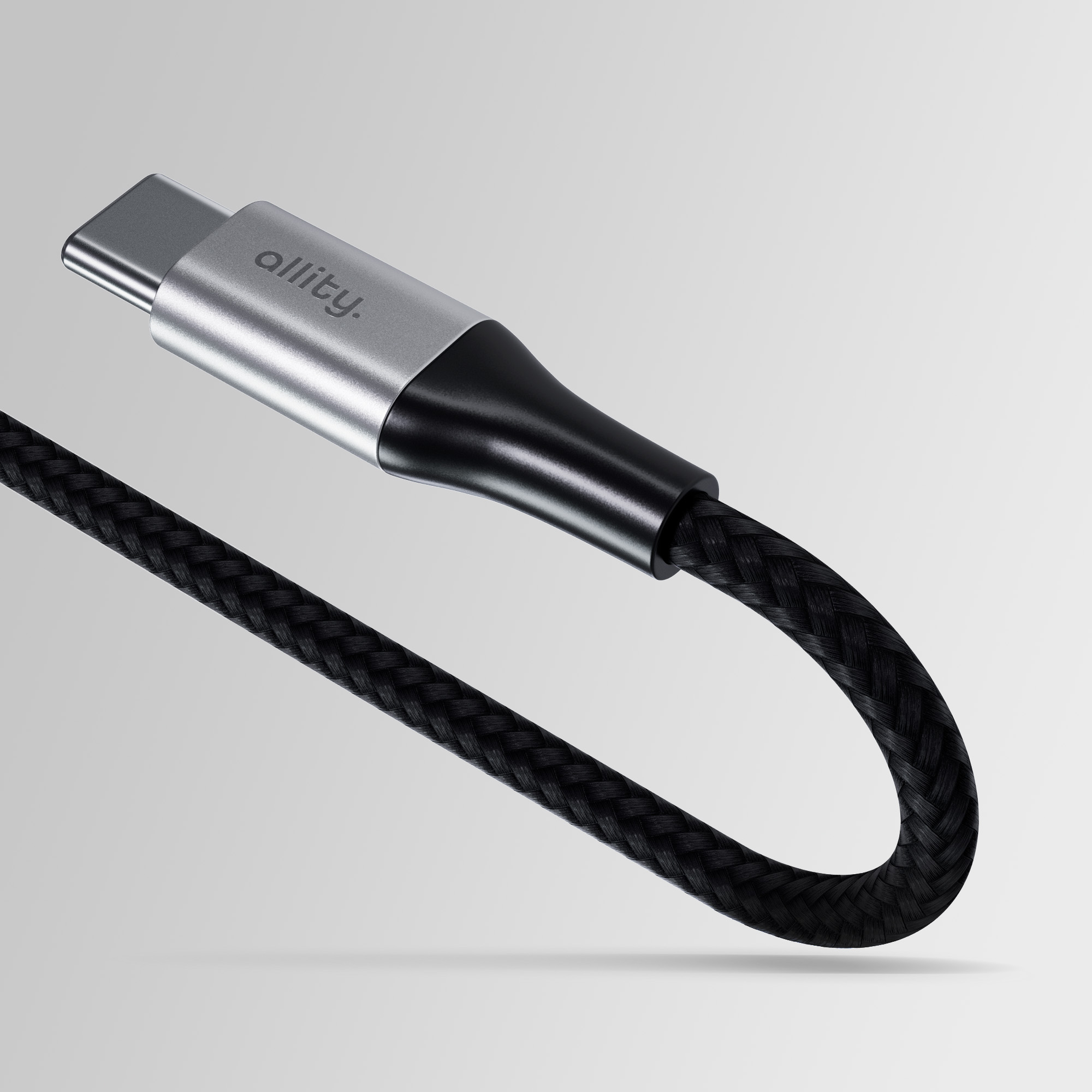 Pleciony czarny kabel USB-C ze srebrną głowicą i czarnym końcem, na jasnoszarym tle.