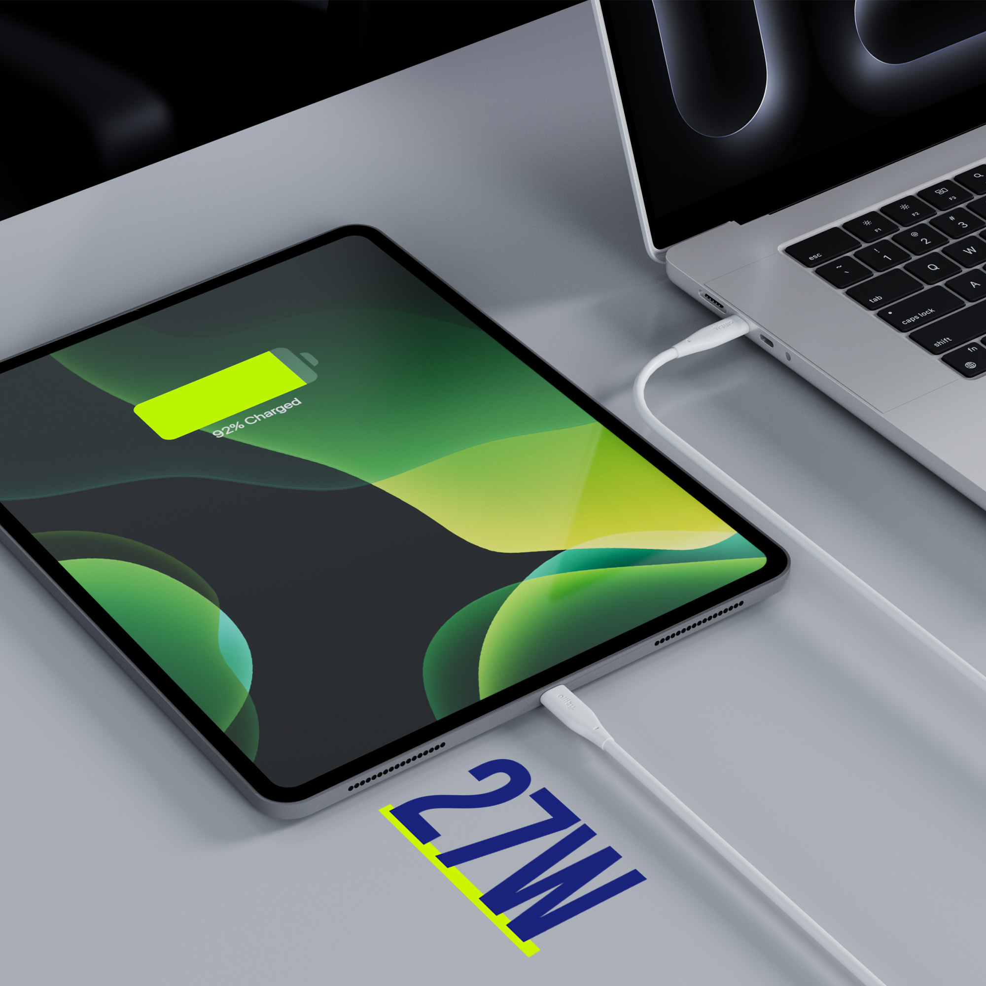Tablet ładujący się z laptopa. Tablet naładowany w 92%. Tekst: 27W. Szaro-czarna kolorystyka.