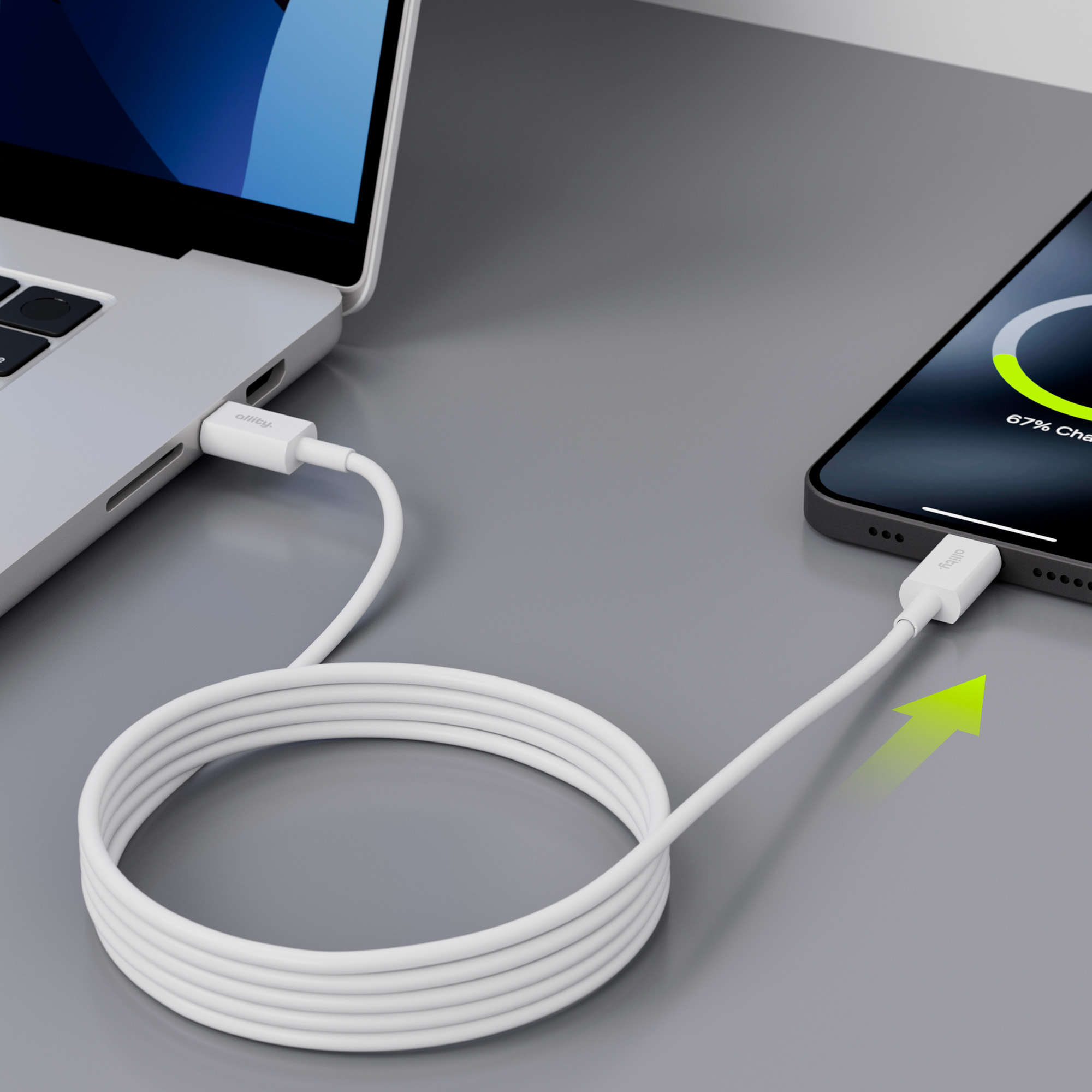 Laptop i telefon w trakcie ładowania. Biały kabel połączony z obydwoma. Telefon pokazuje ładowanie, 67%.