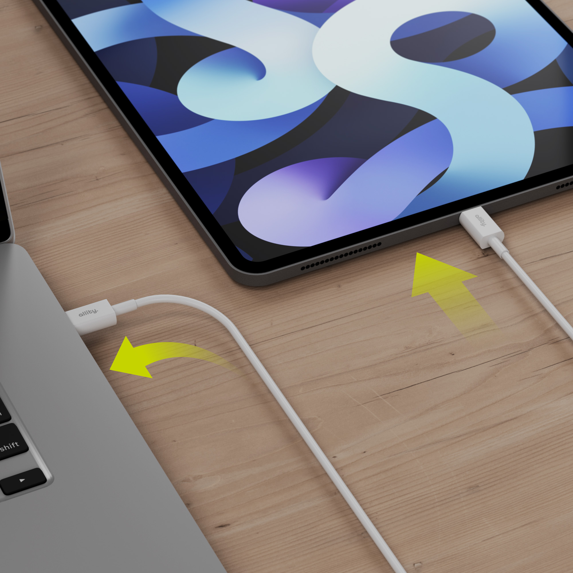 Laptop i tablet połączone białym kablem ładującym ze strzałkami wskazującymi kierunek.