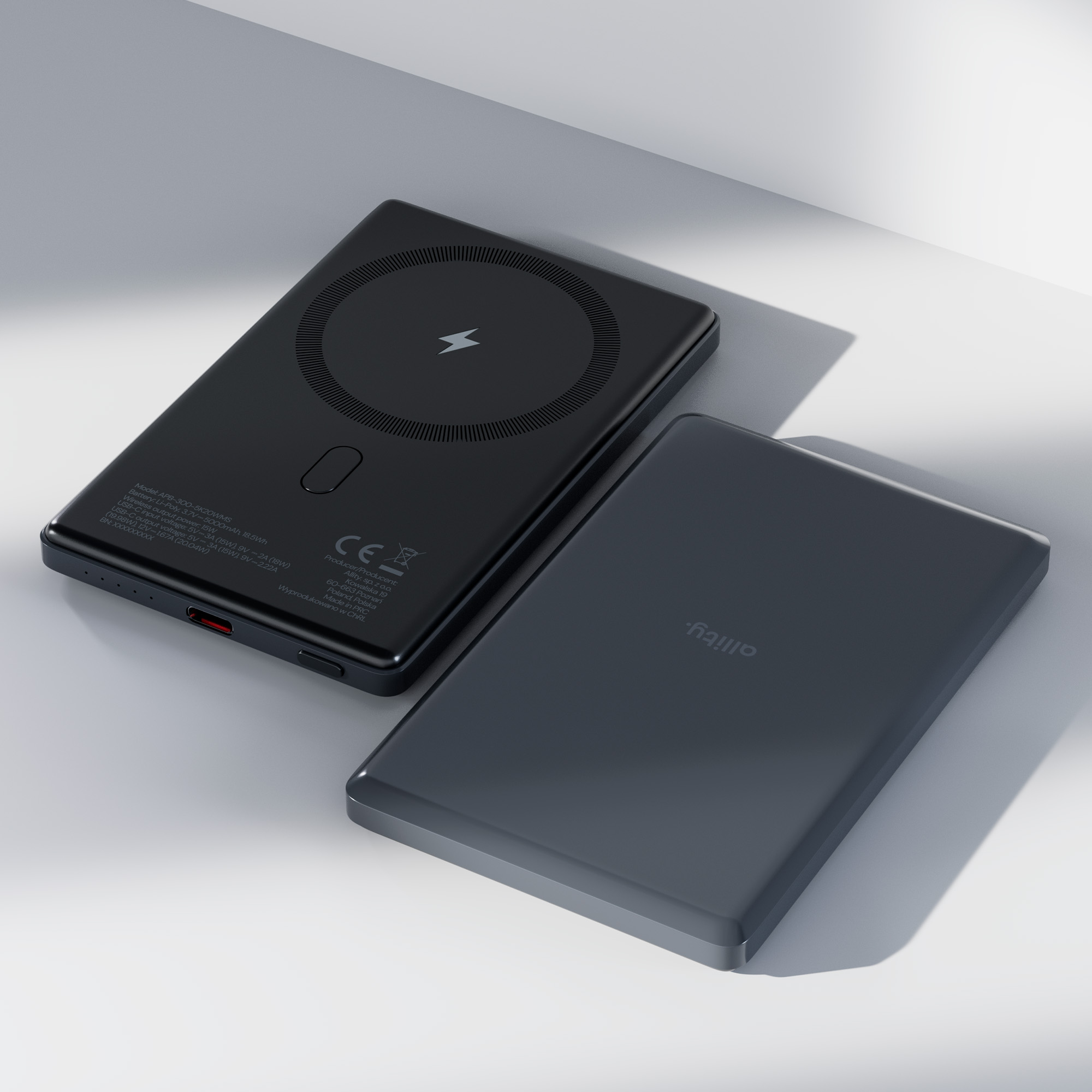 Dwa czarne power banki, jeden z okrągłym symbolem ładowania, na białej powierzchni.