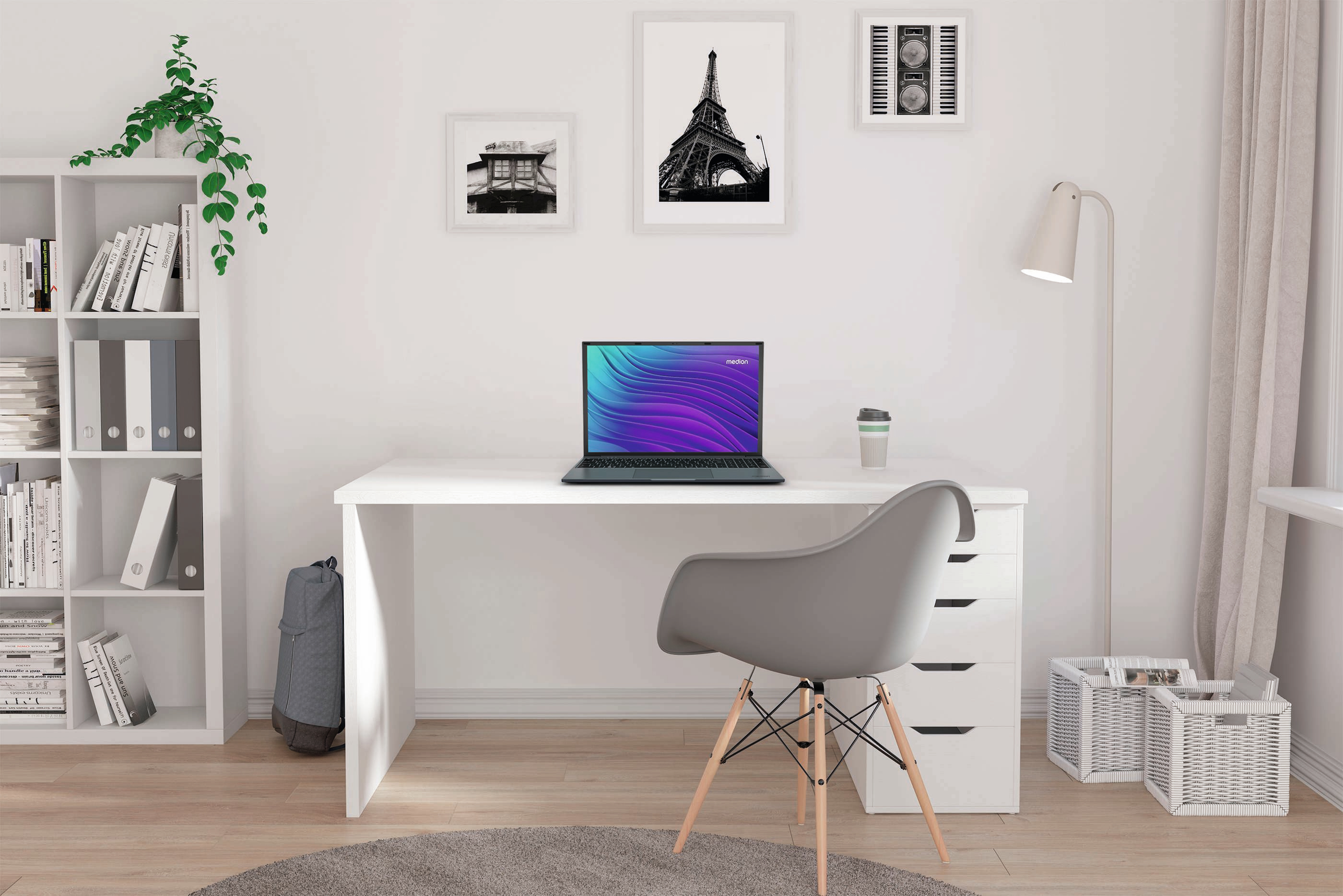 Laptop na białym biurku, w pobliżu okna, krzesła, półki na książki i dekoracji.