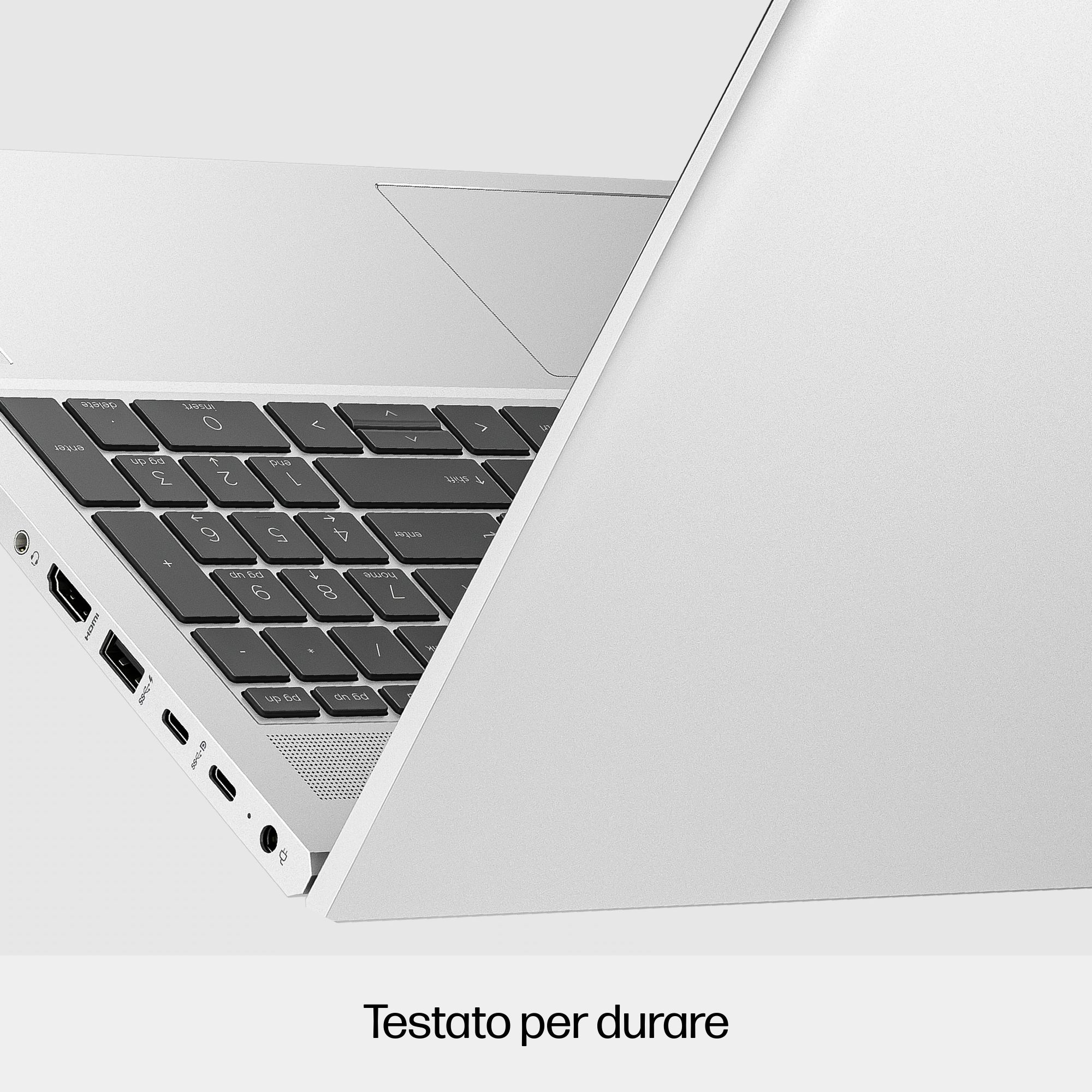 Un laptop argentato è parzialmente aperto, mostrando la tastiera e le porte. Ha un design pulito e minimalista.