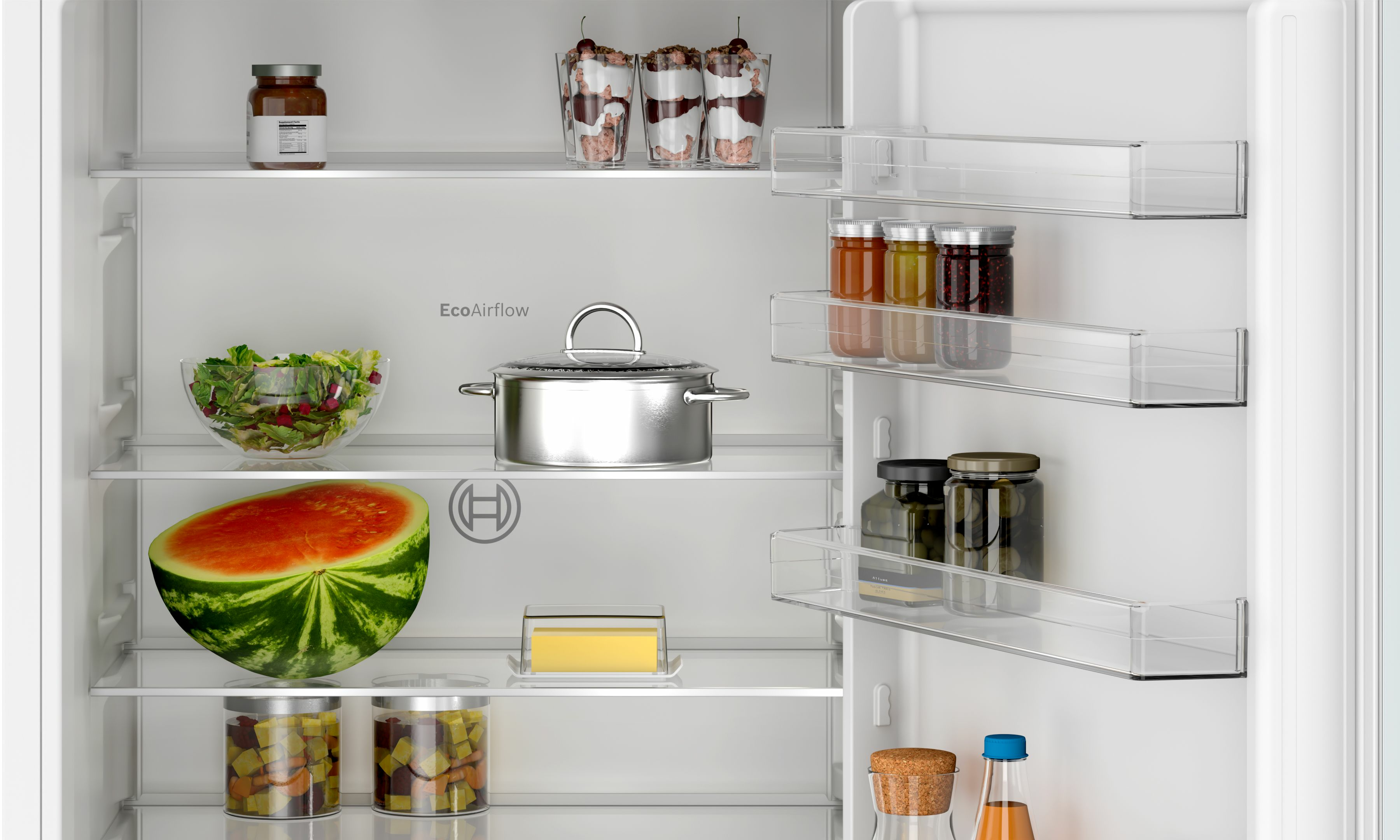Interno frigorifero aperto con alimenti sugli scaffali, tra cui mezza anguria.