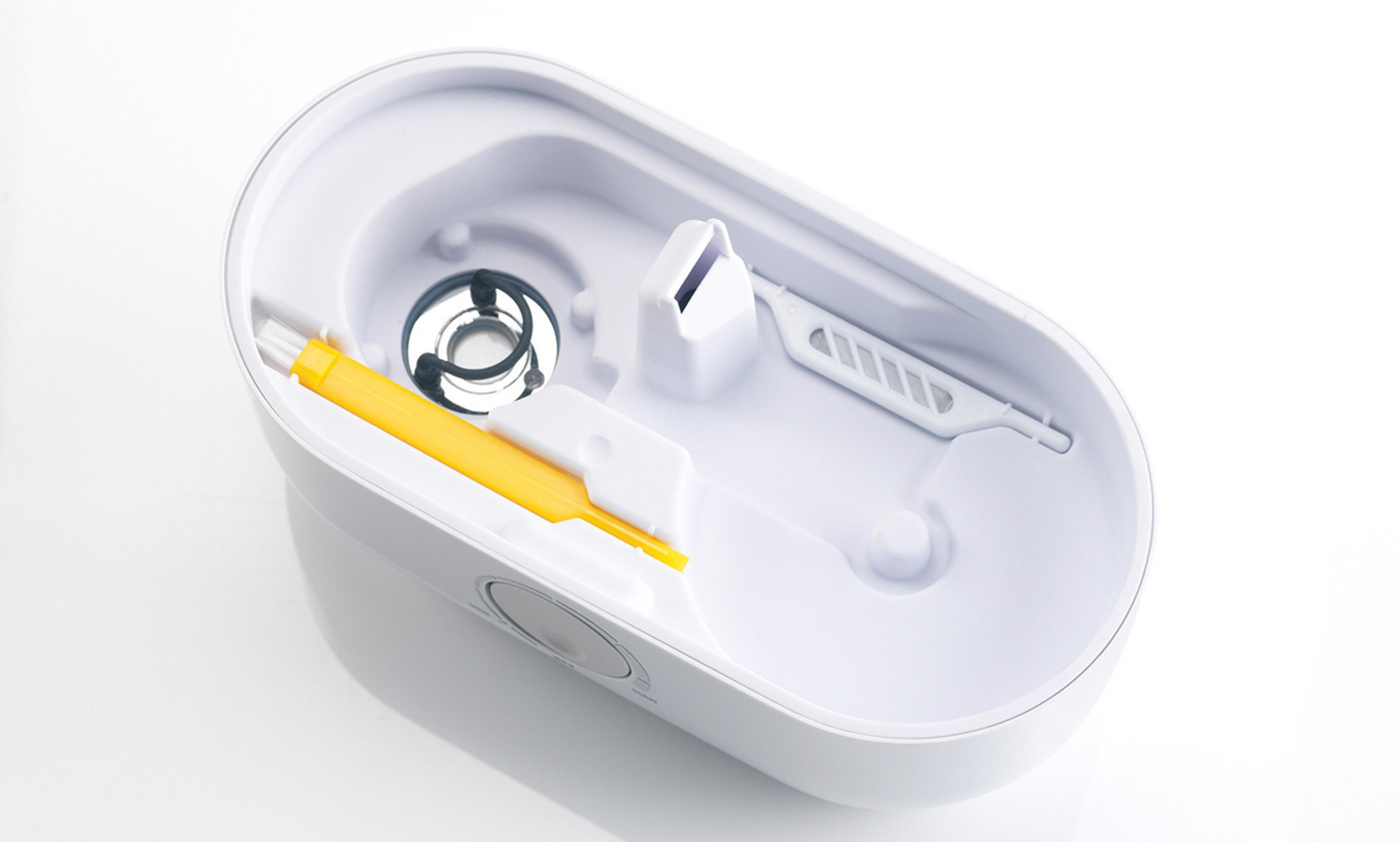 Récipient ovale blanc avec accessoires à l'intérieur. Comprend une brosse jaune et un filtre blanc.
