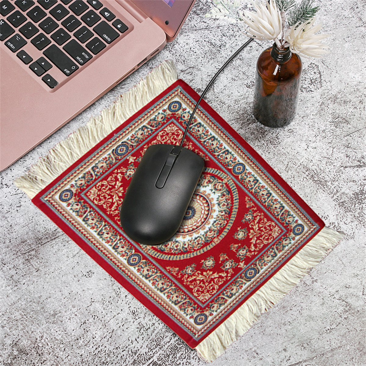 Ein rotes und cremefarbenes Mousepad mit einer schwarzen Maus darauf, in der Nähe eines Laptops.