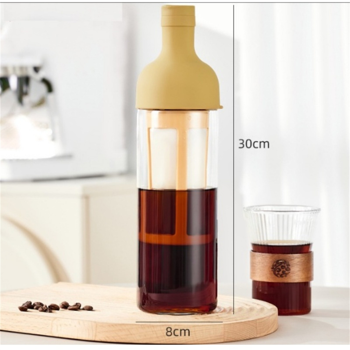 Glasflasche mit dunkler Flüssigkeit und gelbem Deckel. Kaffeebohnen und ein Glas sind vorhanden.