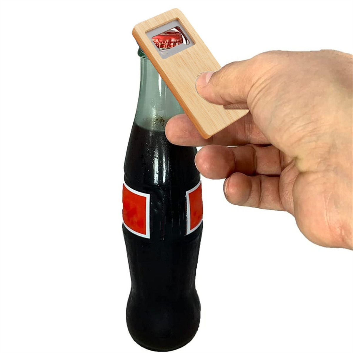 Hand öffnet eine Coca-Cola-Flasche mit einem hölzernen Öffner.