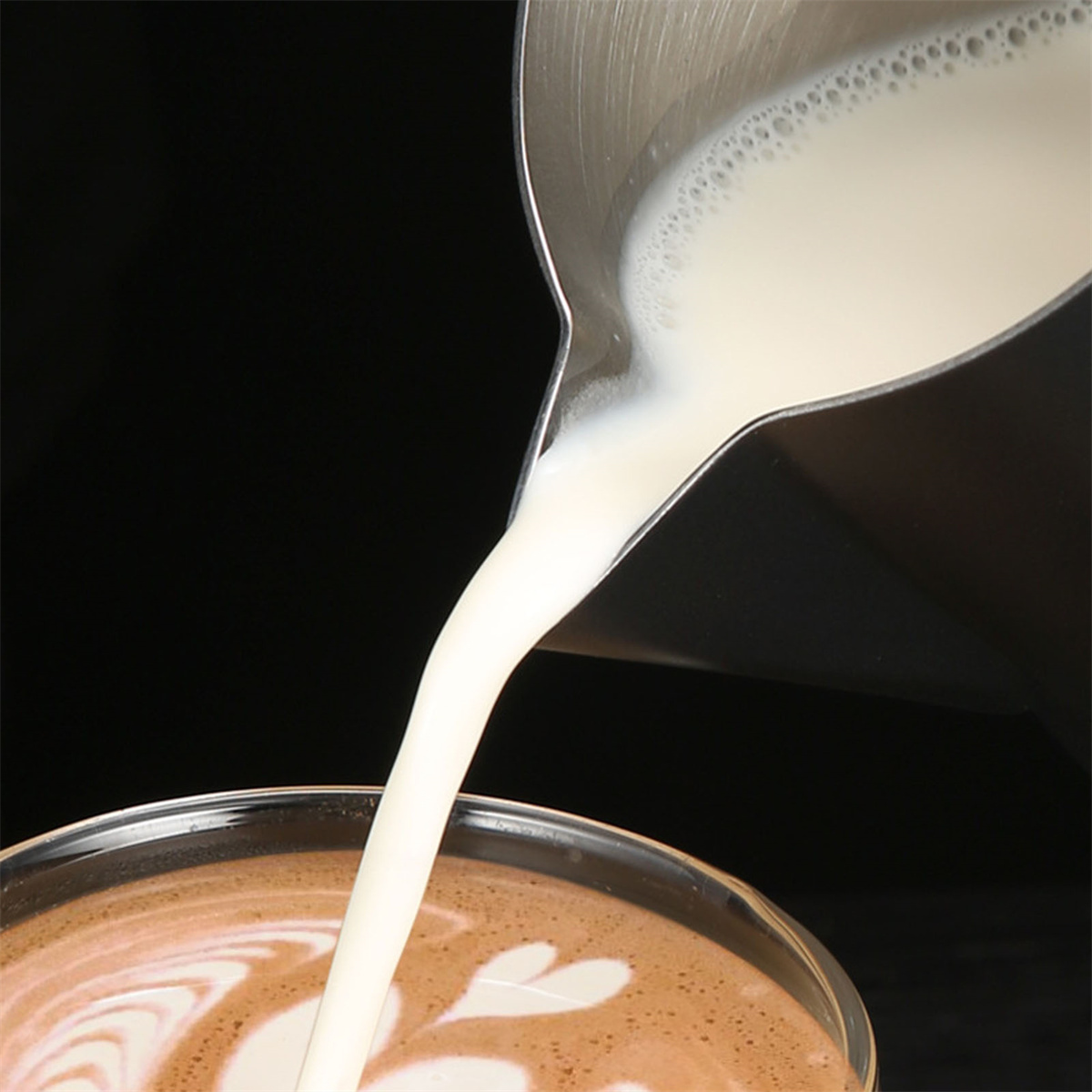 Milch wird in eine Tasse Kaffee gegossen und erzeugt Latte Art.