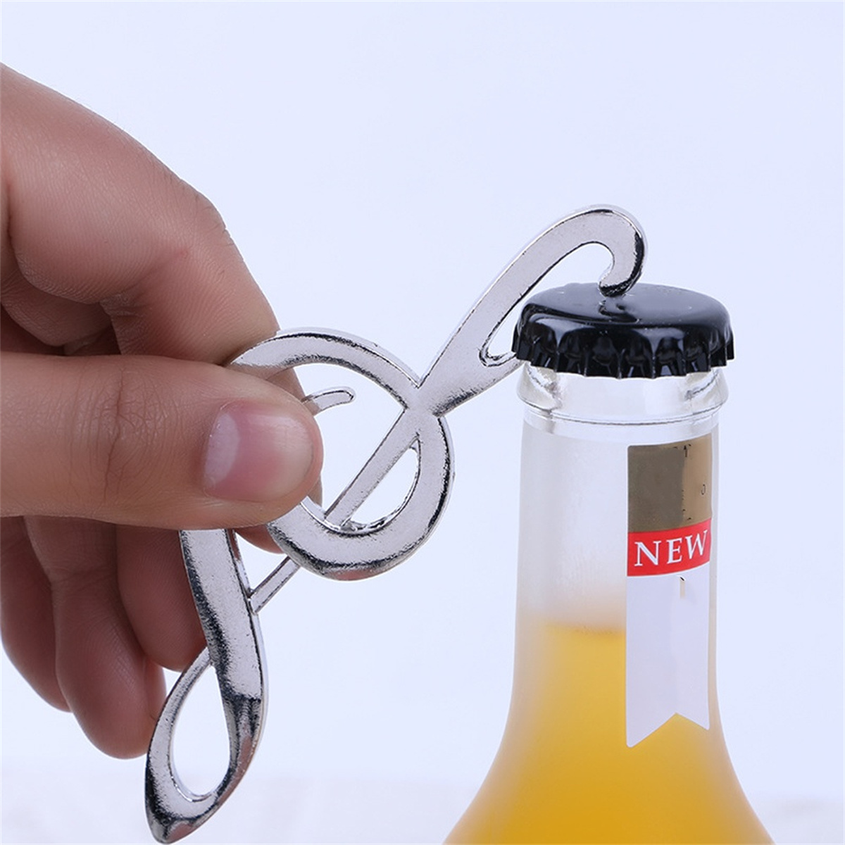 Ein silberner Notenschlüssel-Flaschenöffner öffnet eine Flasche mit einem 'NEU'-Etikett.