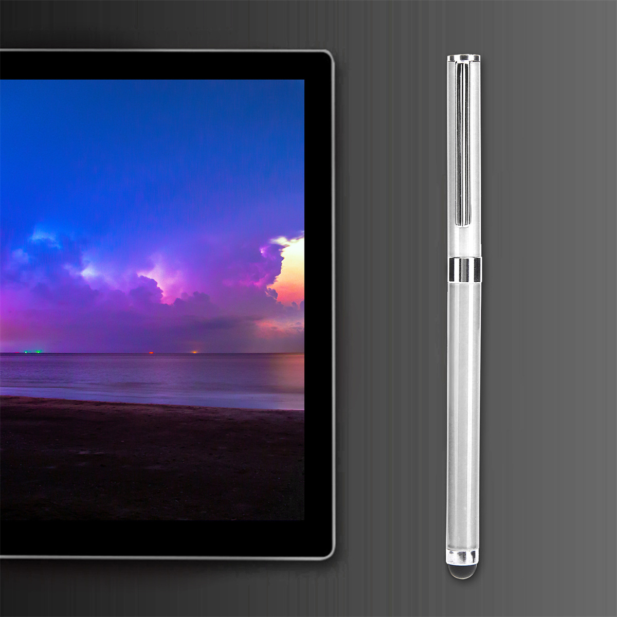 Tablet mit Strand-Sonnenuntergangsszene. Ein silberner Stift liegt auf grauer Oberfläche.