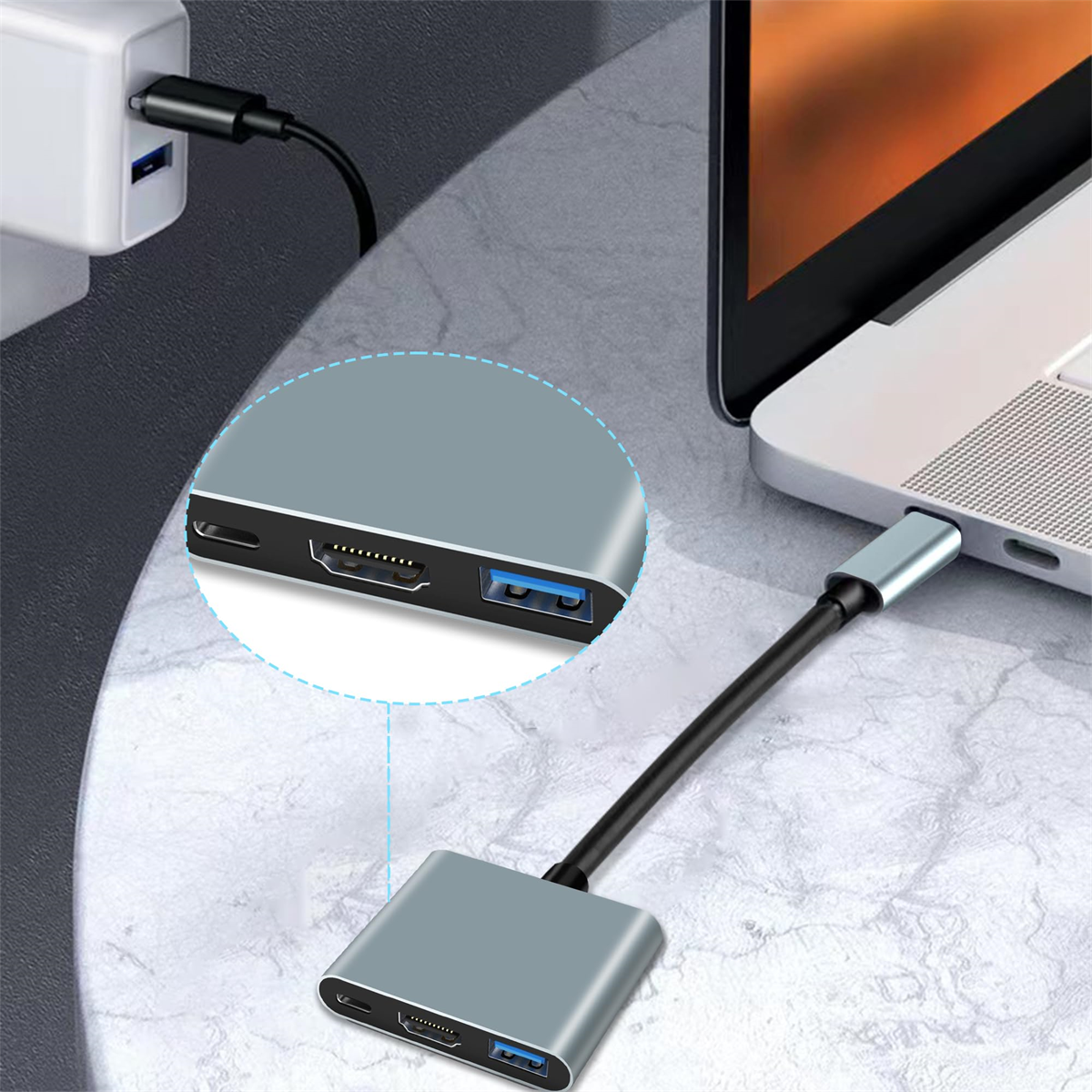 Ein grauer Adapter, der an einen Laptop und ein Ladegerät angeschlossen ist, mit Nahaufnahme der Adapteranschlüsse.