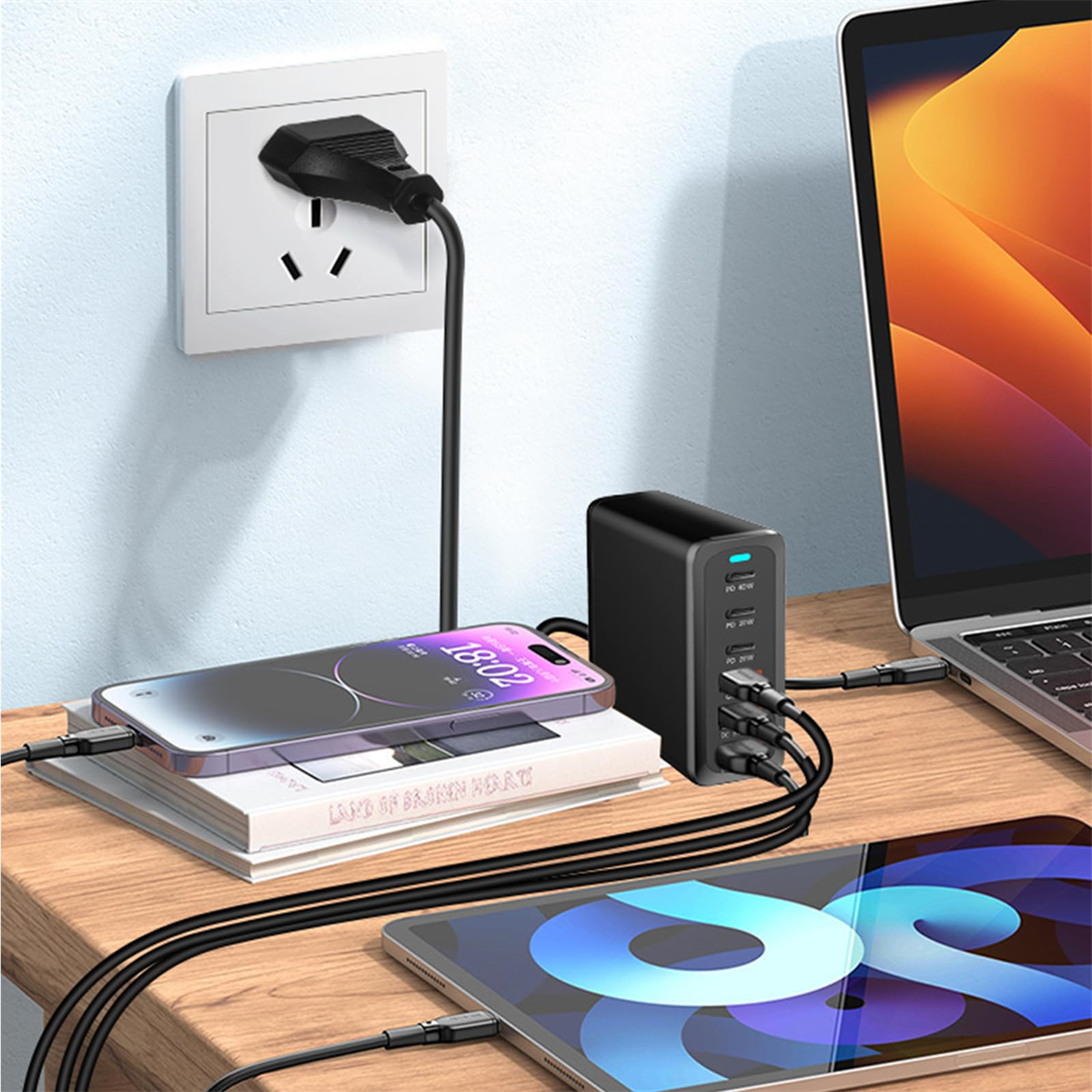 Schwarze Ladestation mit Telefon, Tablet, Laptop und Stecker in der Steckdose.