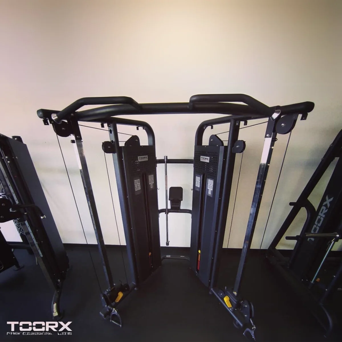 Gym met een kabel crossover machine, en twee andere trainingsmachines.