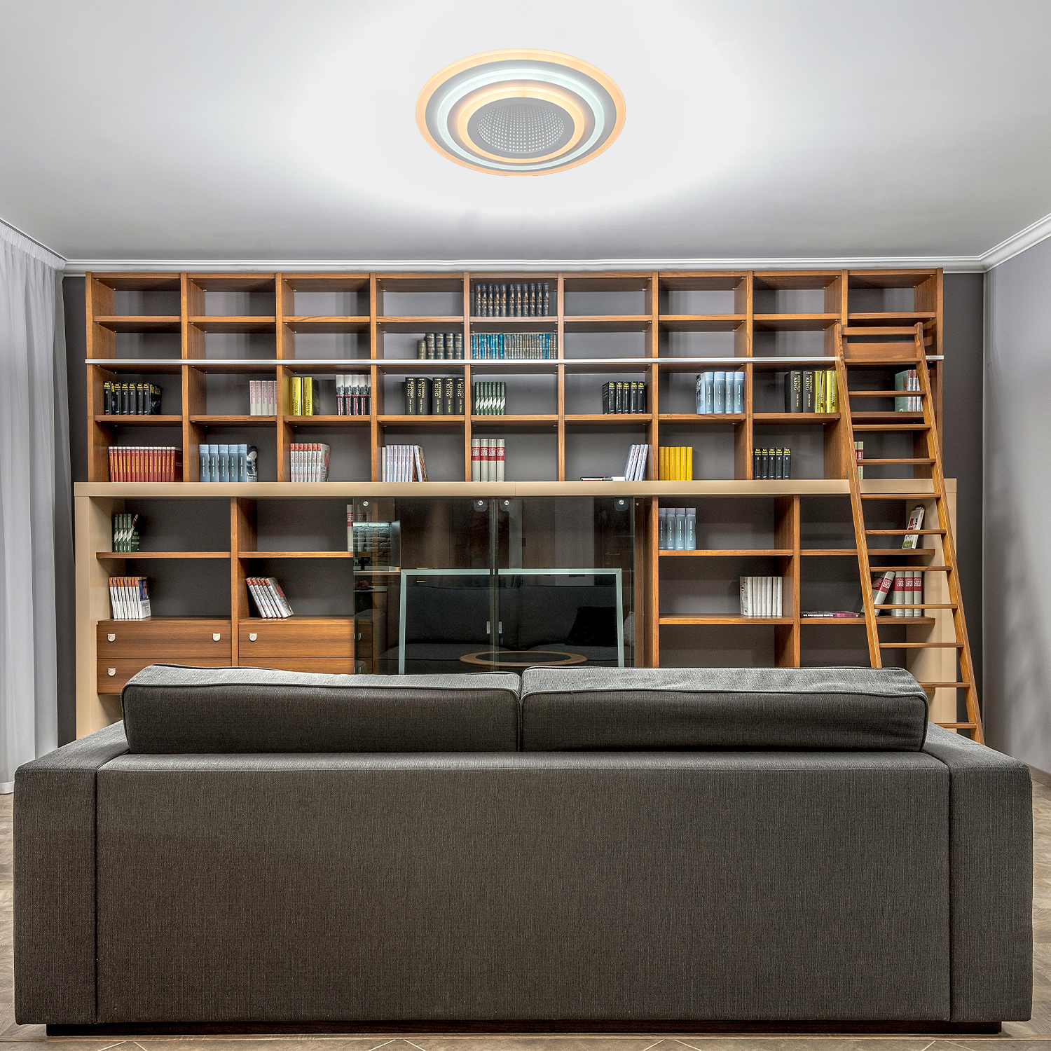 Interno con divano, libreria in legno e lampada da soffitto. Scaffali, scala, TV e lampada concentrica.