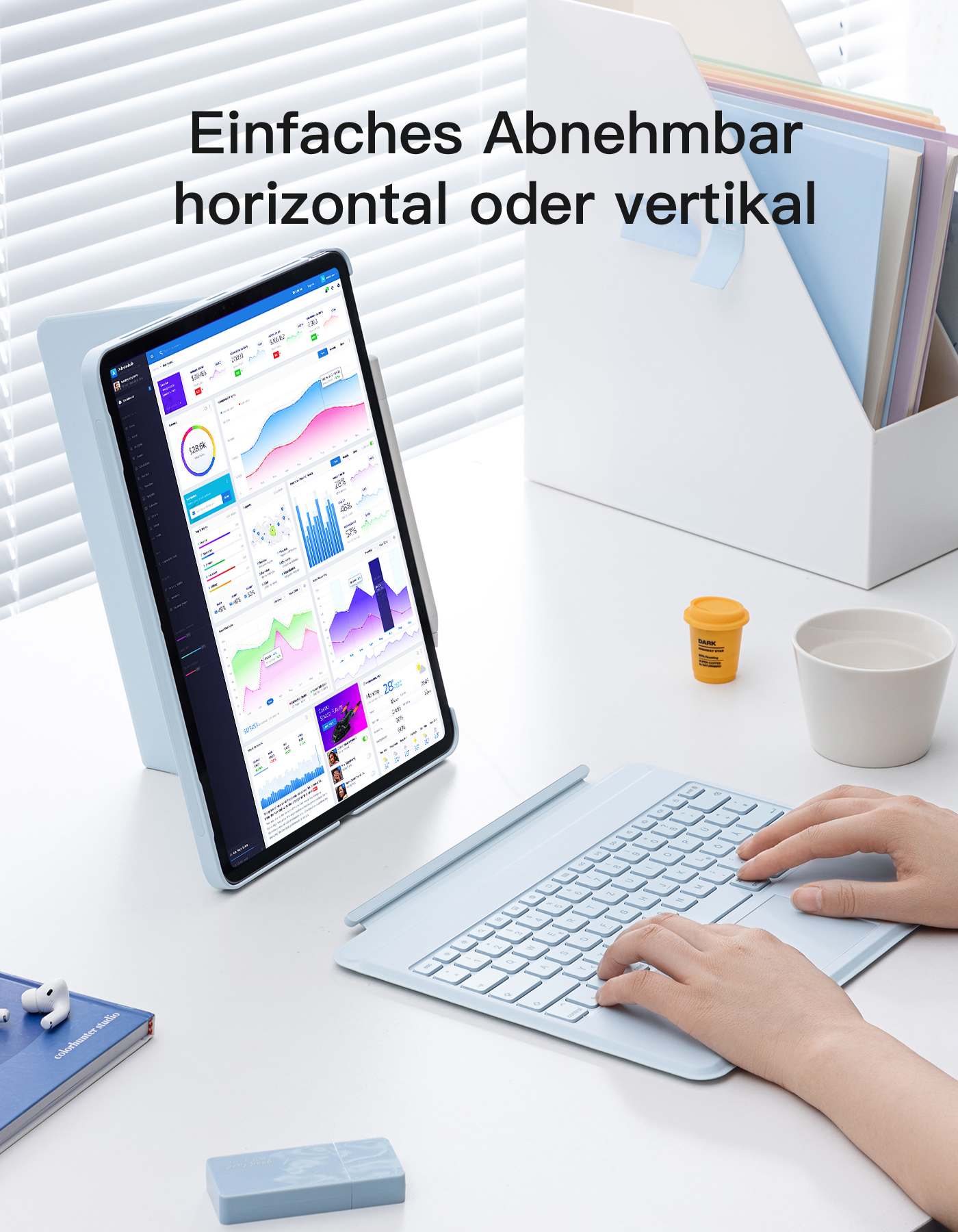 Tablet mit Tastatur auf dem Schreibtisch. Eine Hand tippt. Hintergrund: Ordner, eine Tasse und ein Stifthalter.
