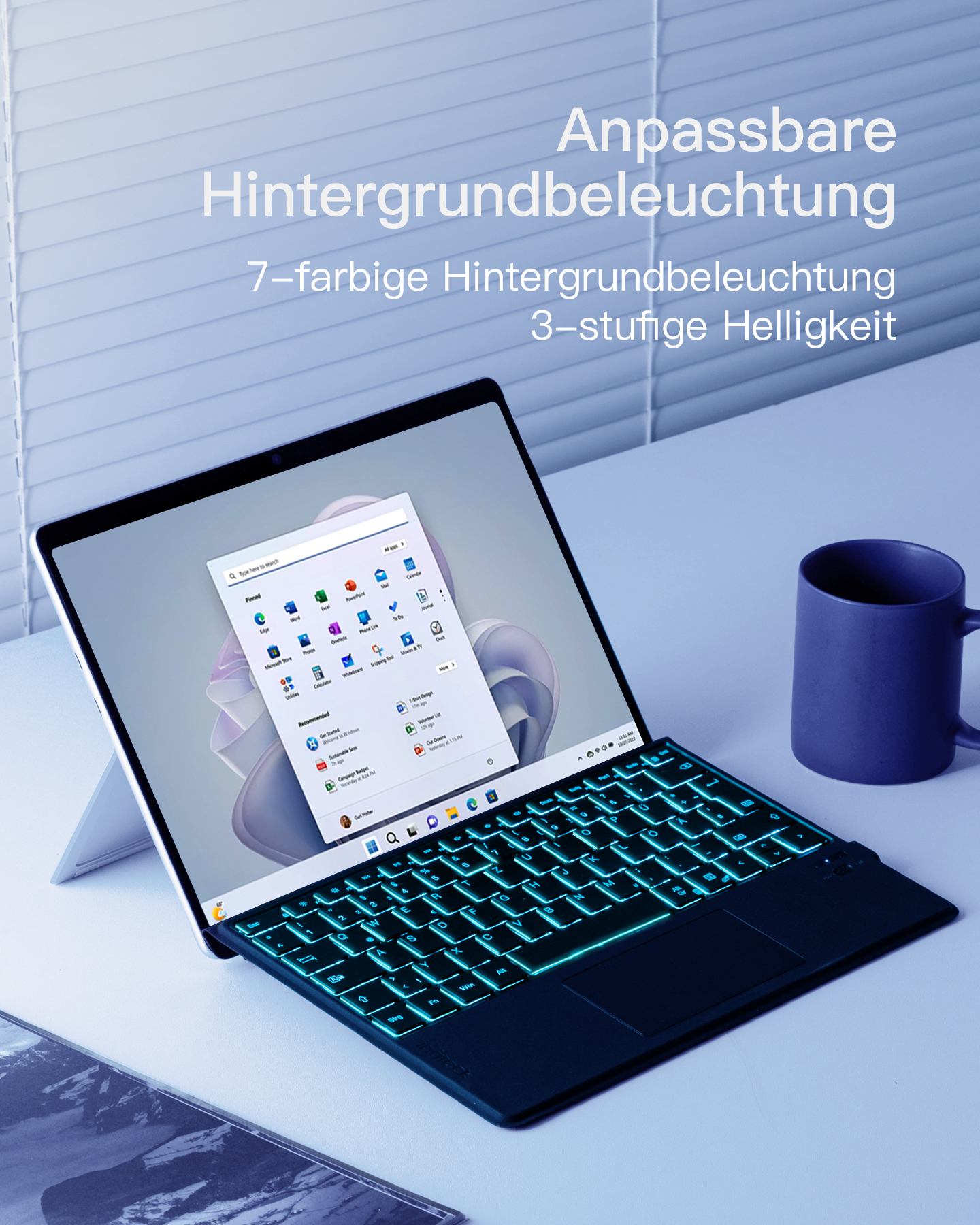 Laptop mit beleuchteter Tastatur und Tasse auf weißem Tisch.