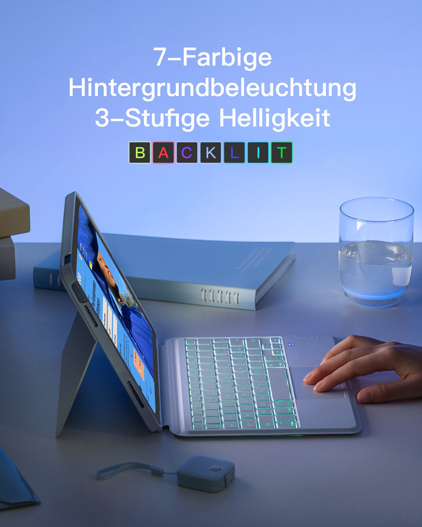Ein Tablet mit Tastatur liegt auf einem weißen Tisch. Rechts ein Glas Wasser.