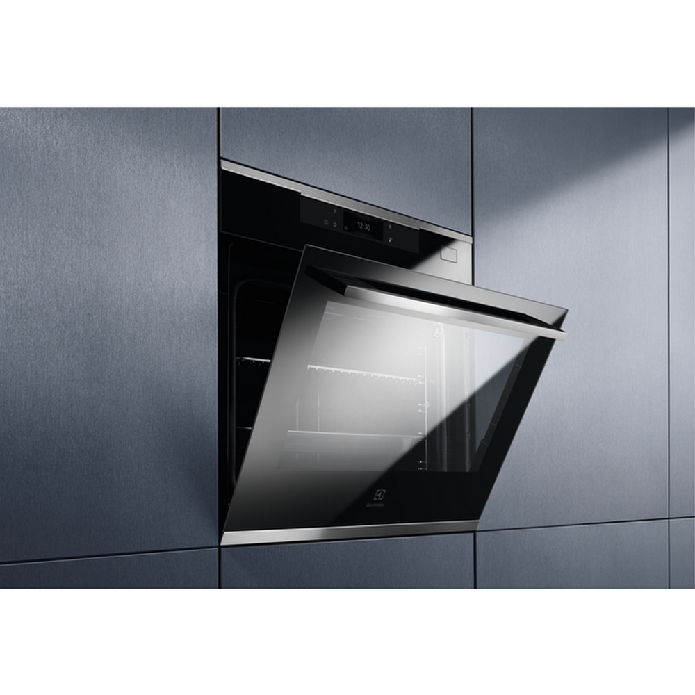 Un forno moderno con una porta in vetro riflettente, incastonato in mobili grigi.