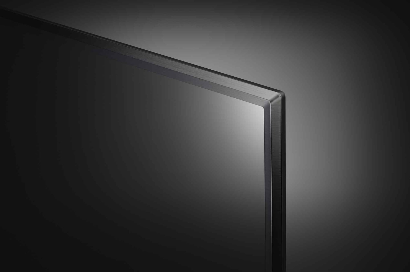Primer plano de una esquina de pantalla de TV. Pantalla negra, marco metálico, fondo oscuro.