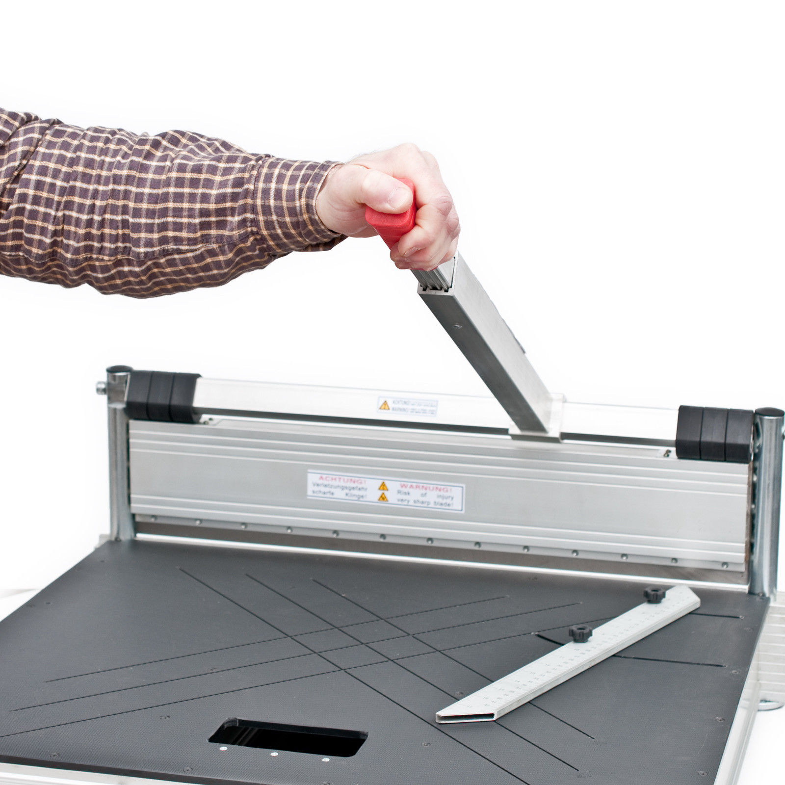 Eine Person schneidet Papier mit einem Papierschneider. Roter Griff und silberne Klinge.
