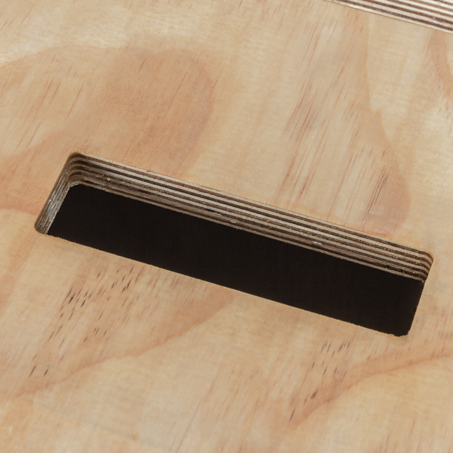 Nahaufnahme eines Holzbretts mit einem rechteckigen schwarzen Ausschnitt und sichtbarer Holzmaserung.