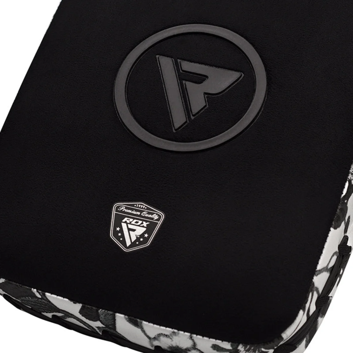Black boxing pad with a circular logo and a shield logo, against a white and black floral background.