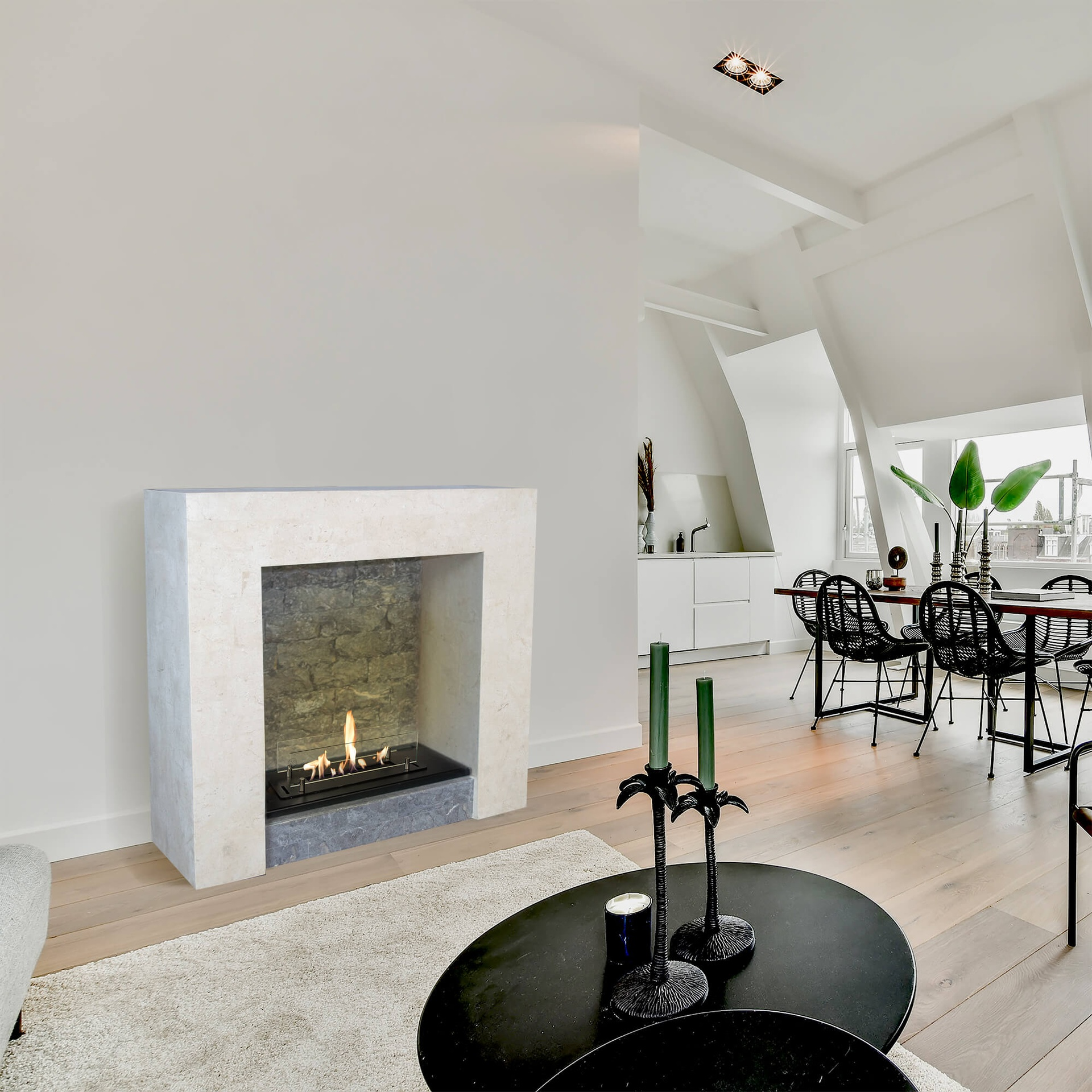 Living room with fireplace, dining area. Black tables with candles. Light wood floor. White walls and ceiling.