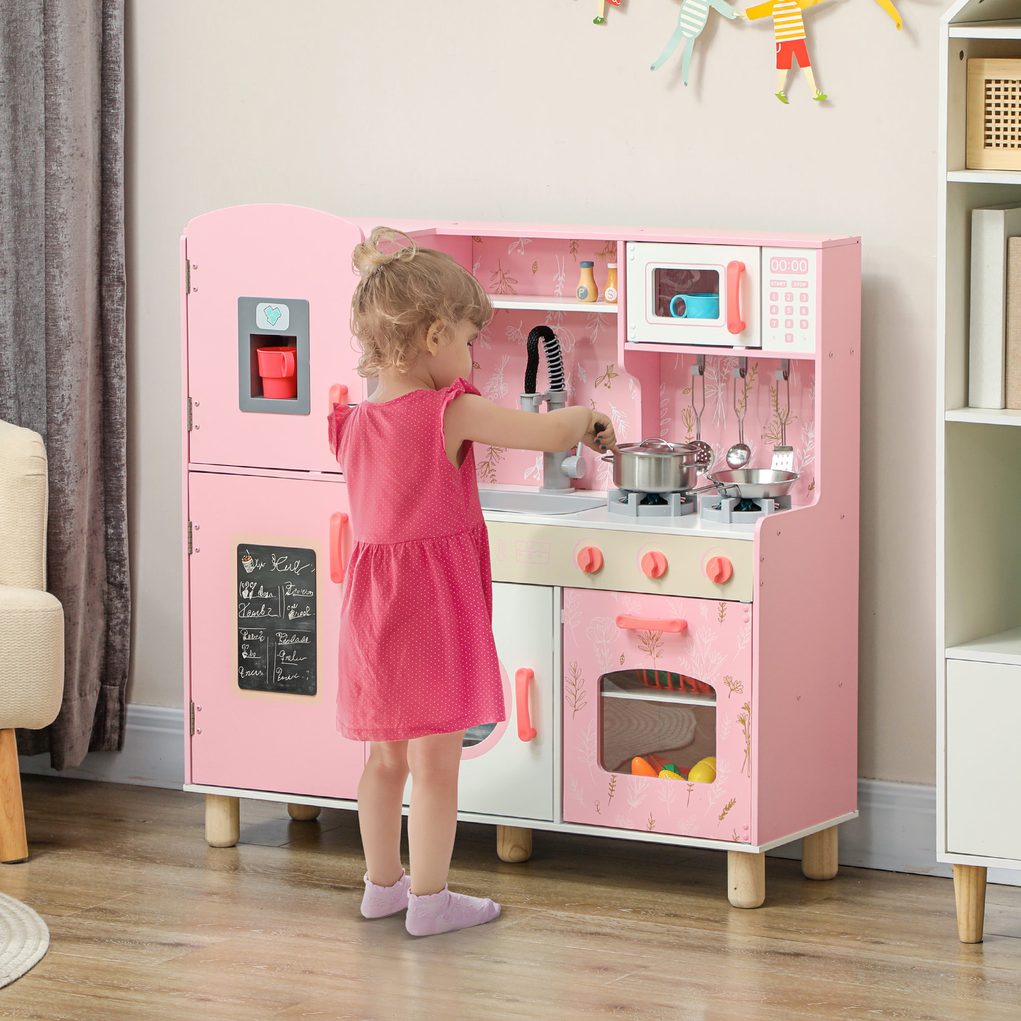 Una niña jugando con una cocina de juguete rosa, con accesorios y electrodomésticos.