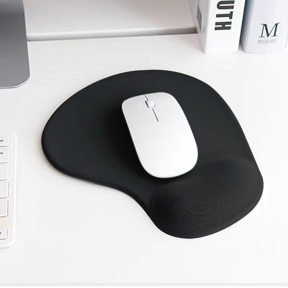 Schwarze Maus und schwarzes Mauspad auf einem weißen Schreibtisch.