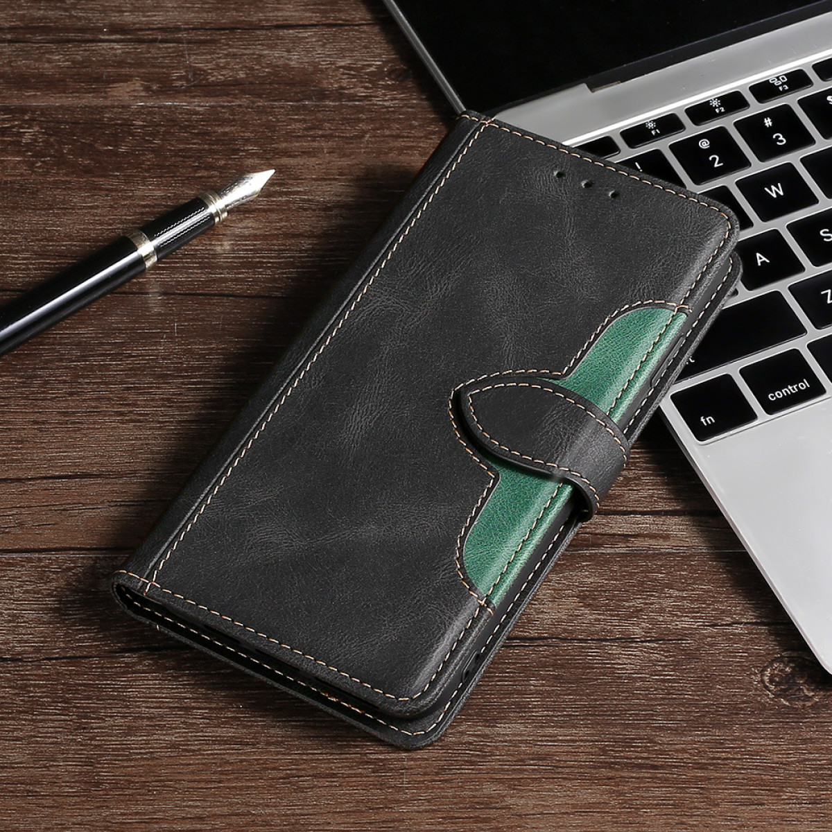 Custodia nera con accento verde, su scrivania in legno con laptop.