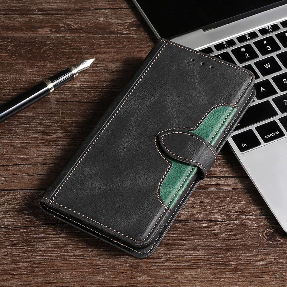 Custodia per telefono in pelle nera e verde su legno con penna e laptop.
