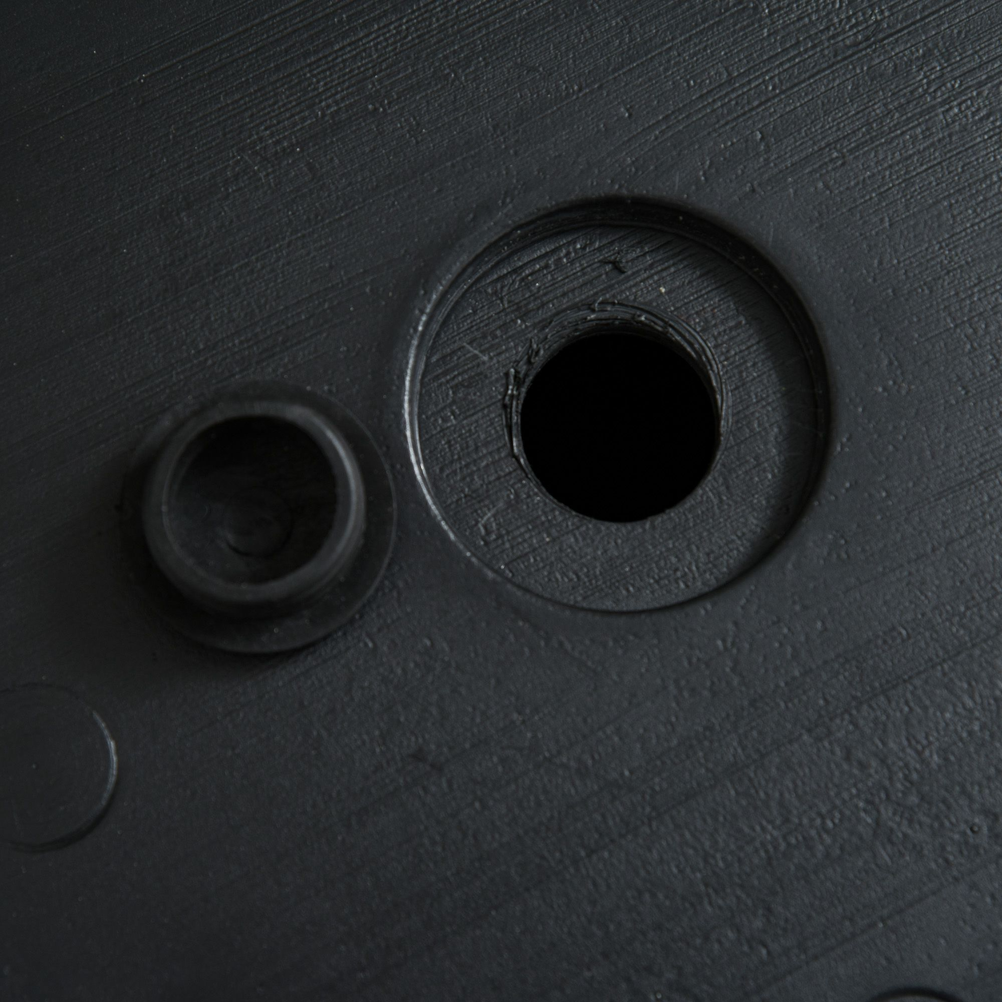 Primer plano de una base negra y circular con un agujero y un círculo más pequeño y elevado.
