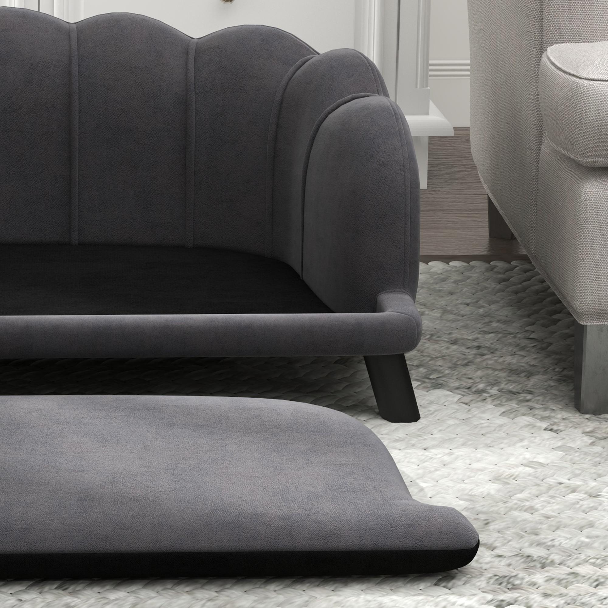 Ein graues Sofa mit Fußstütze, auf einem weißen Teppich. Ein zweites Sofa ist im Hintergrund.