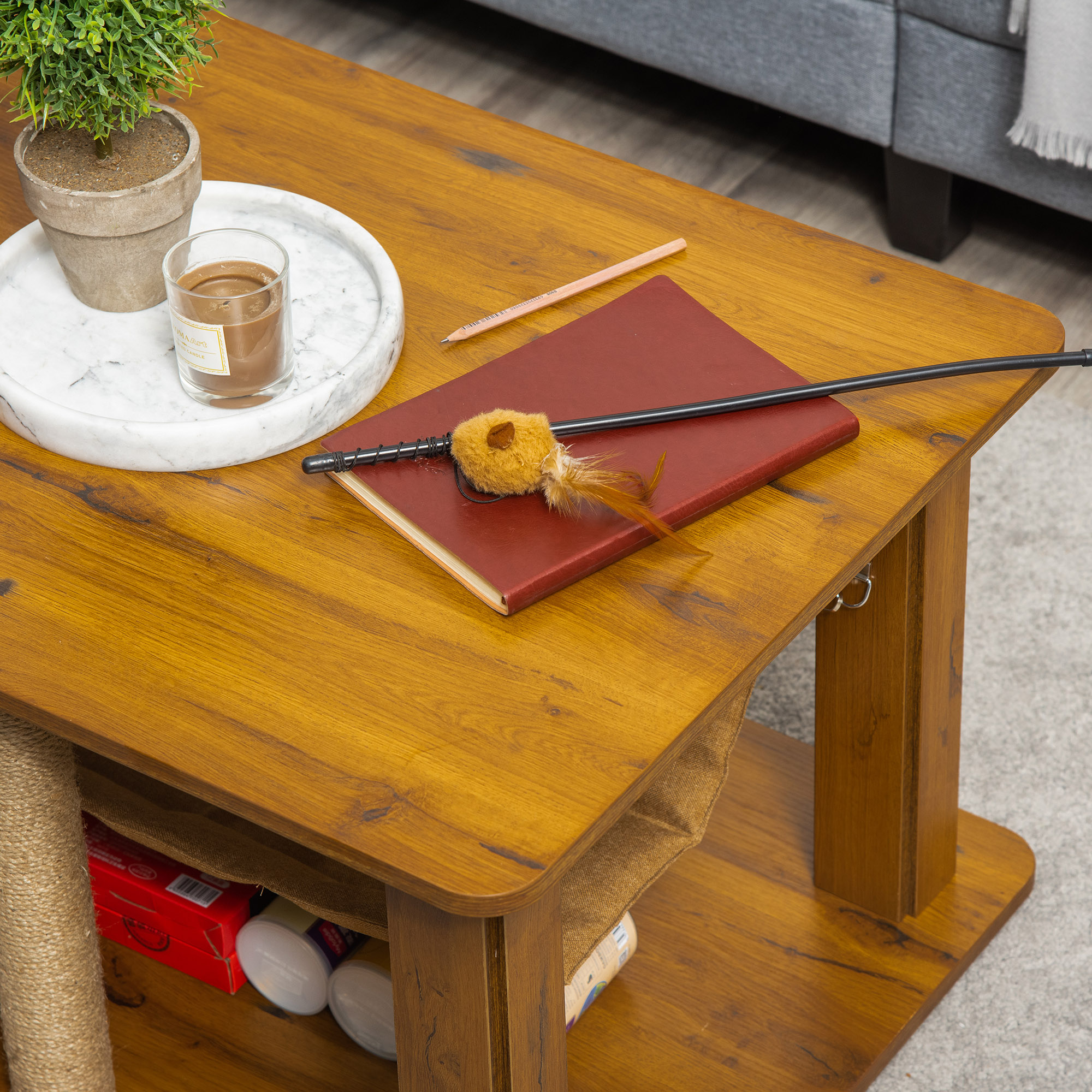 Una mesa de centro de madera con juguetes para gatos, una vela y un libro.